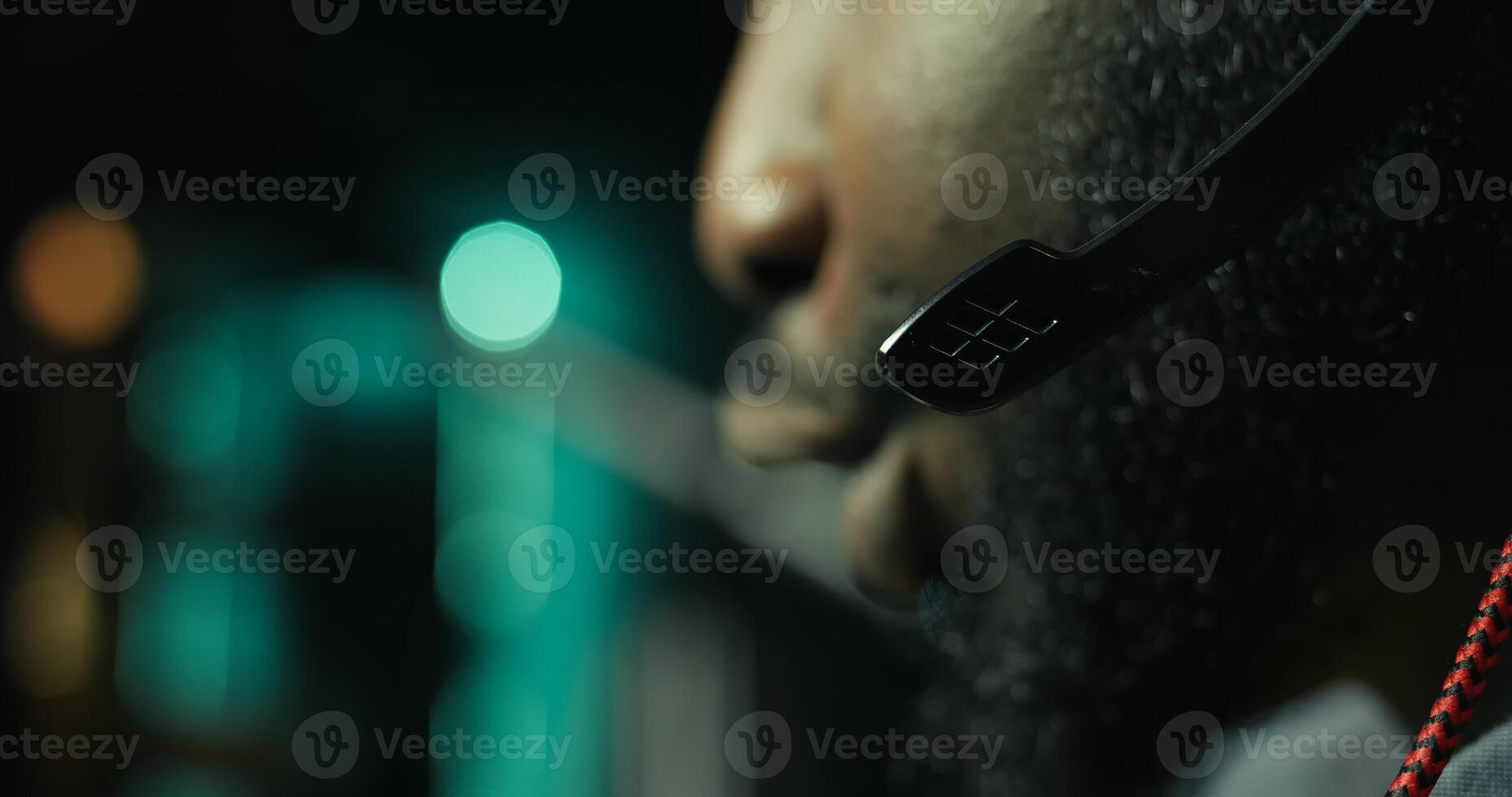 Close up of headset mic used by professional streamer competing in intense online multiplayer videogame live from home. Focus on headphones microphone used by man playing on gaming PC, camera B photo