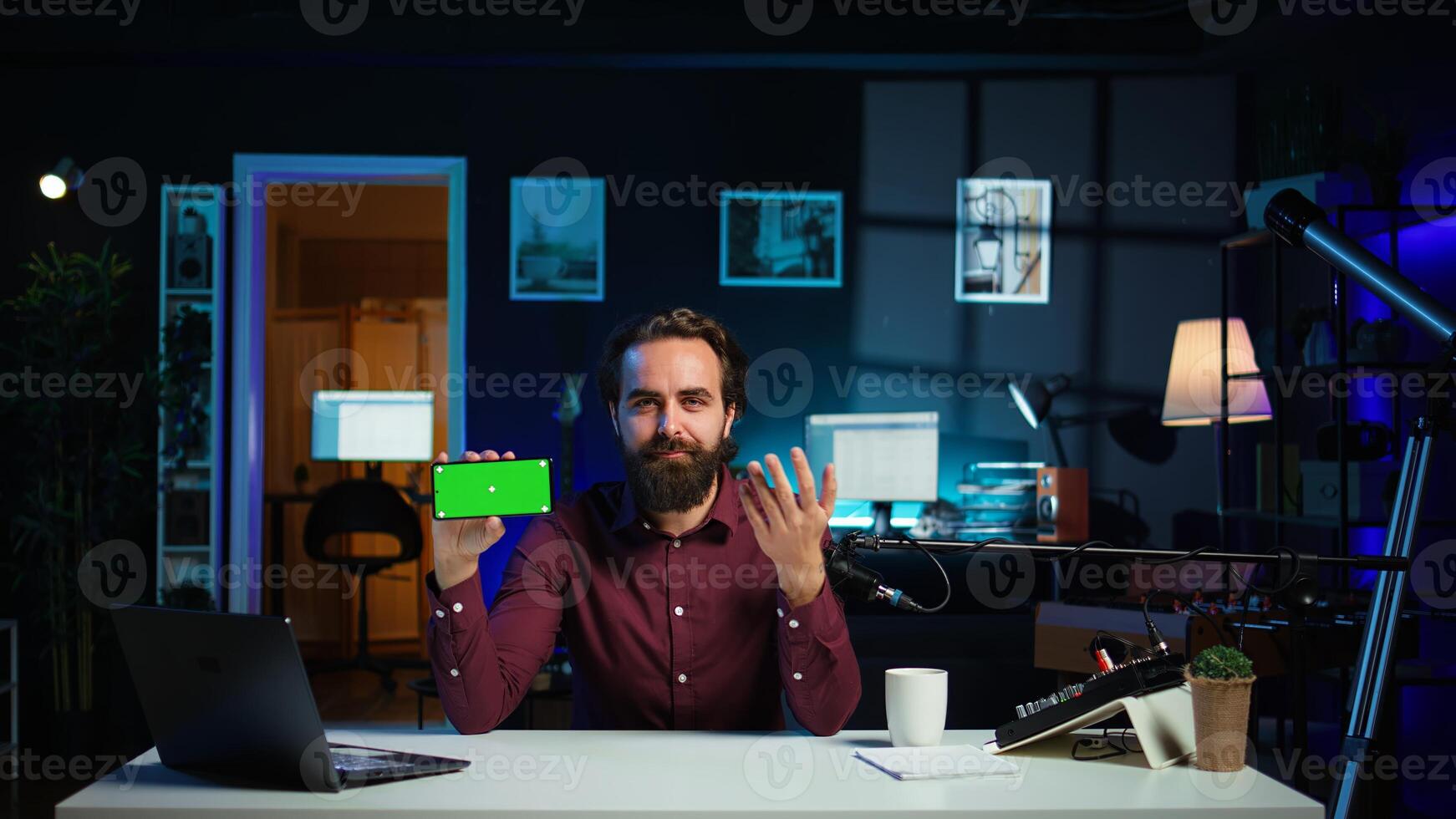 Man showing green screen cellphone, using it as empty copy space to showcase his online streaming channel logo. Media star does introductory using chroma key phone, camera B photo