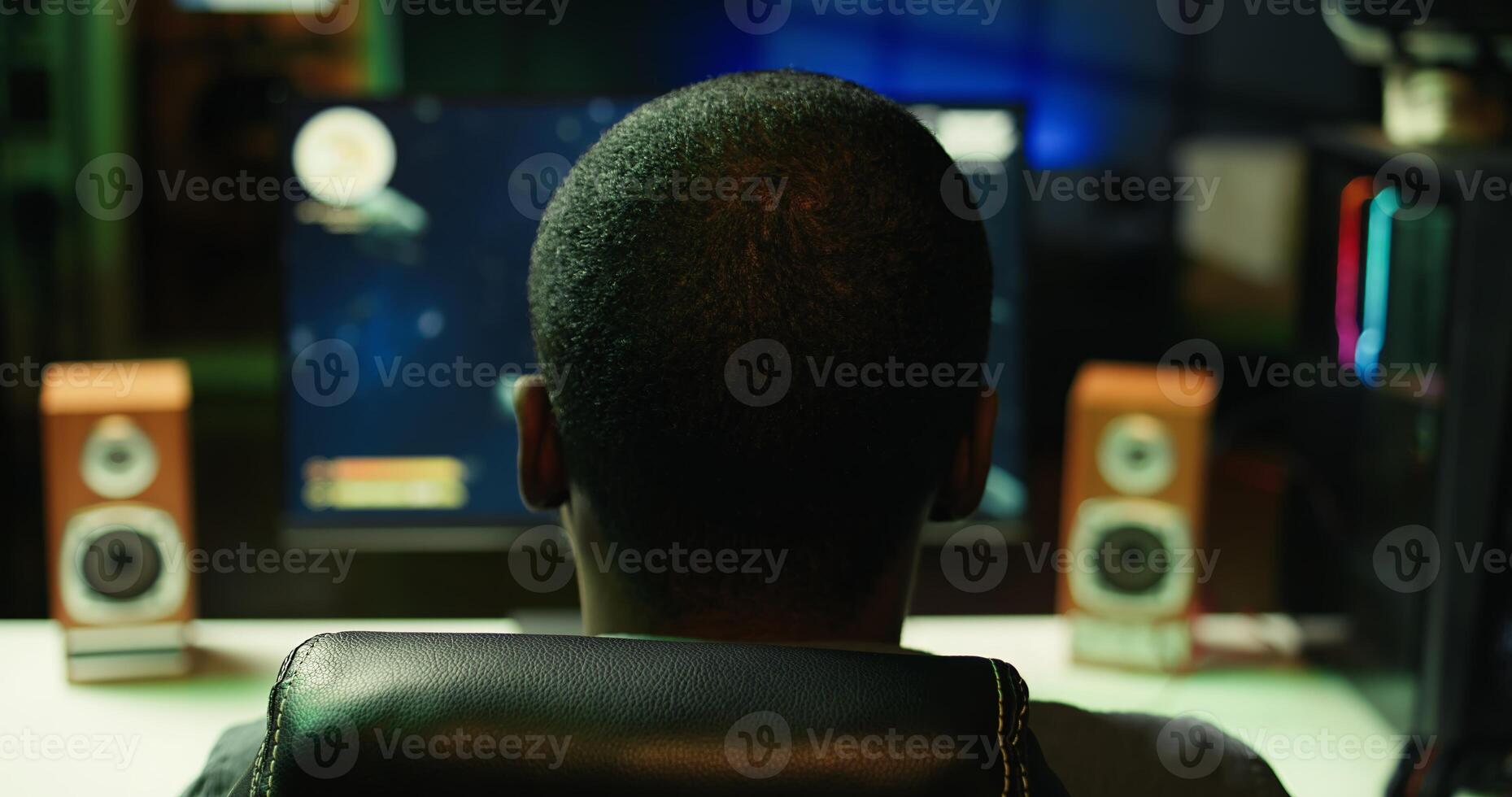 Gamer plays online multiplayer spaceship videogame with friends, relaxing in dark room. Player talking with teammates, flying spacecraft, enjoying leisure time in neon lights adorn apartment, camera B photo