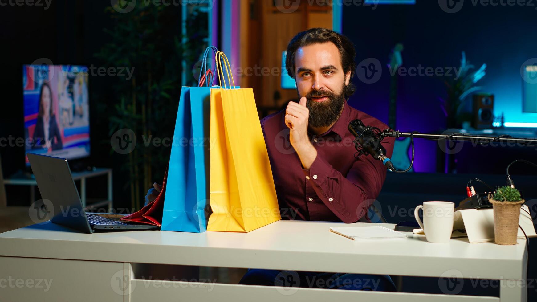Upbeat influencer holding colorful shopping bags in hand, showing subscribers purchases he recently got. Cheerful content creator presenting fanbase new acquisitions, camera A photo