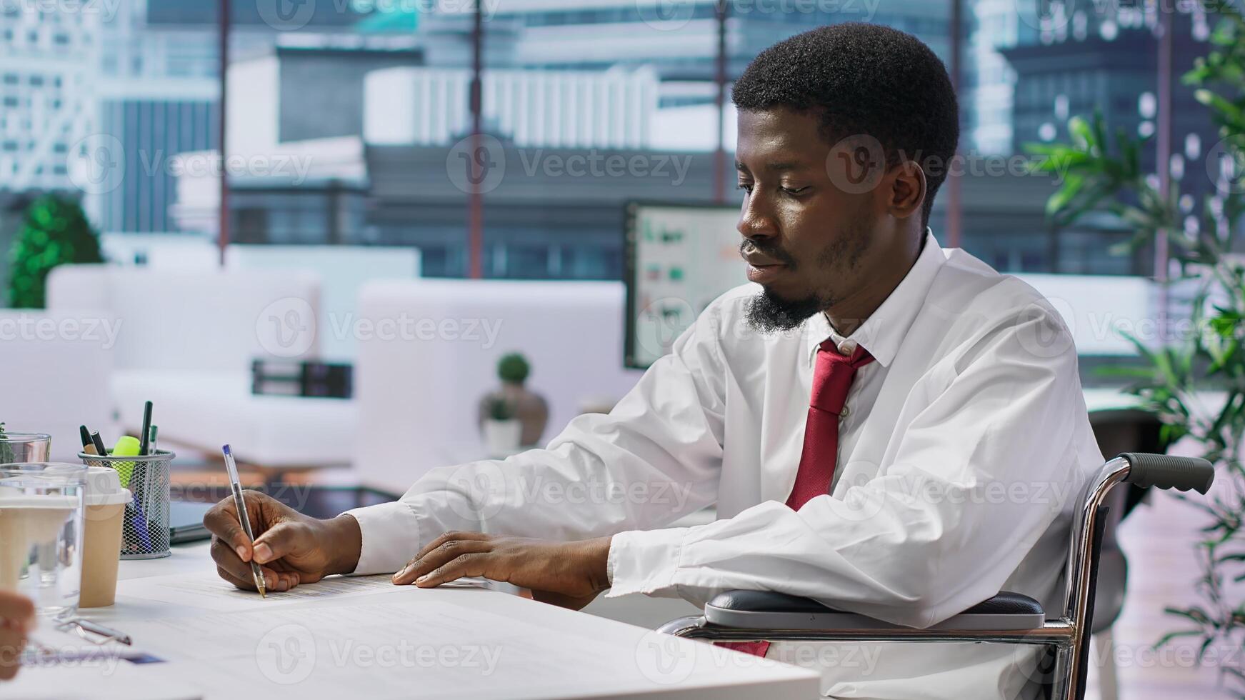 Wheelchair user job seeker fills in application form during interview, discuss with HR team about assistive integration within the company. Disability friendly inclusive adaptive office. Camera A. photo
