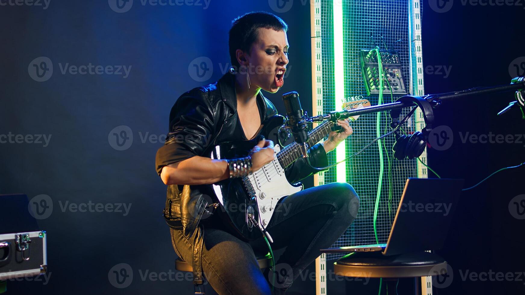 Pleased punk rock artist rehearsing for her live performance, focusing on vocal training and warm up. Edgy iconic woman enjoying singing practice with alternative music. Camera A. photo