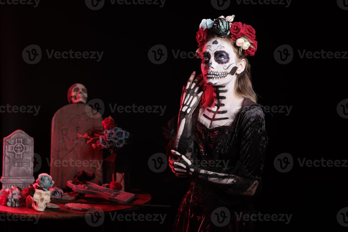 Woman doing Day of the Dead Mexican celebration honoring dead loved ones, building ofrendas for them. Person doing ancient Aztec custom of celebrating ancestors, wearing skull makeup photo