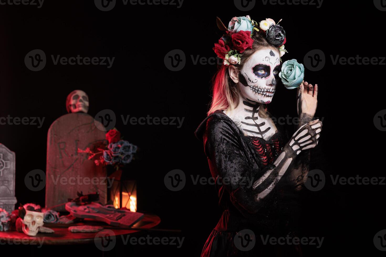Frightening girl posing with blue rose during Dia de los Muertos, preserving cultural traditions between generations. Lady wearing la Catrina character silk dress to celebrate Mexican culture photo