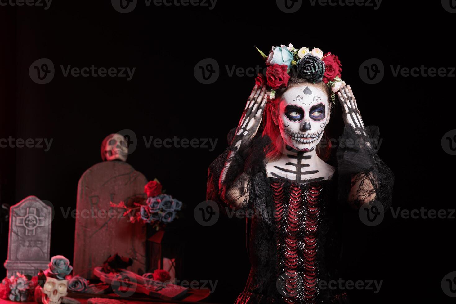 Woman participates in Day of the Dead Mexican event honoring dead loved ones, building altar for them. Lady doing ancient Aztec custom of celebrating ancestors, putting on flower crown photo