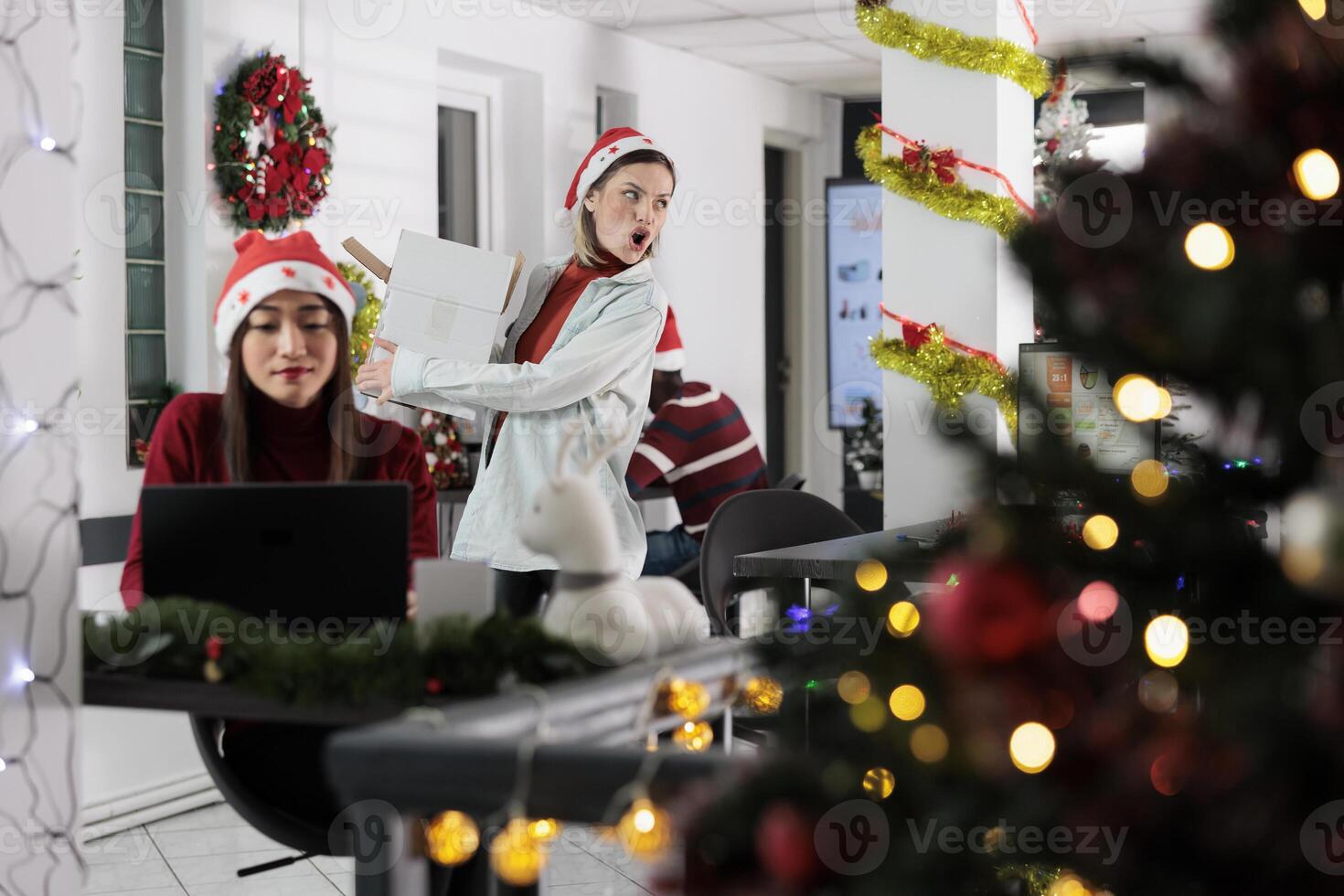 Employee fighting with management, angry about being unreasonably fired from Christmas decorated workplace. Upset worker leaving festive decorated office after notice period expired photo