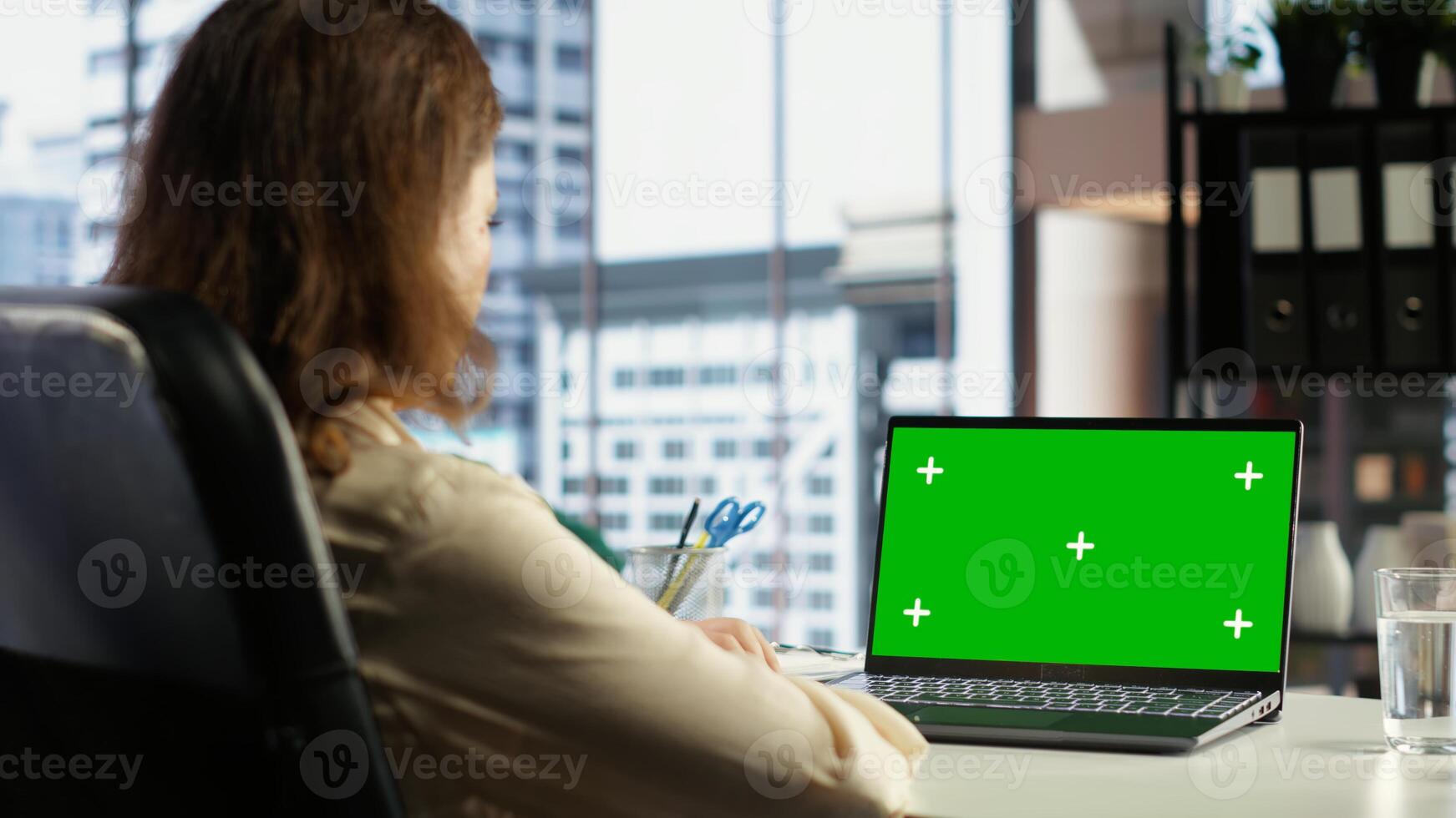 Woman company leader looking at isolated chroma key display in high end urban office, ambitious driven CEO with executive power. Businesswoman with strategic thinking in corporation. Camera B. photo