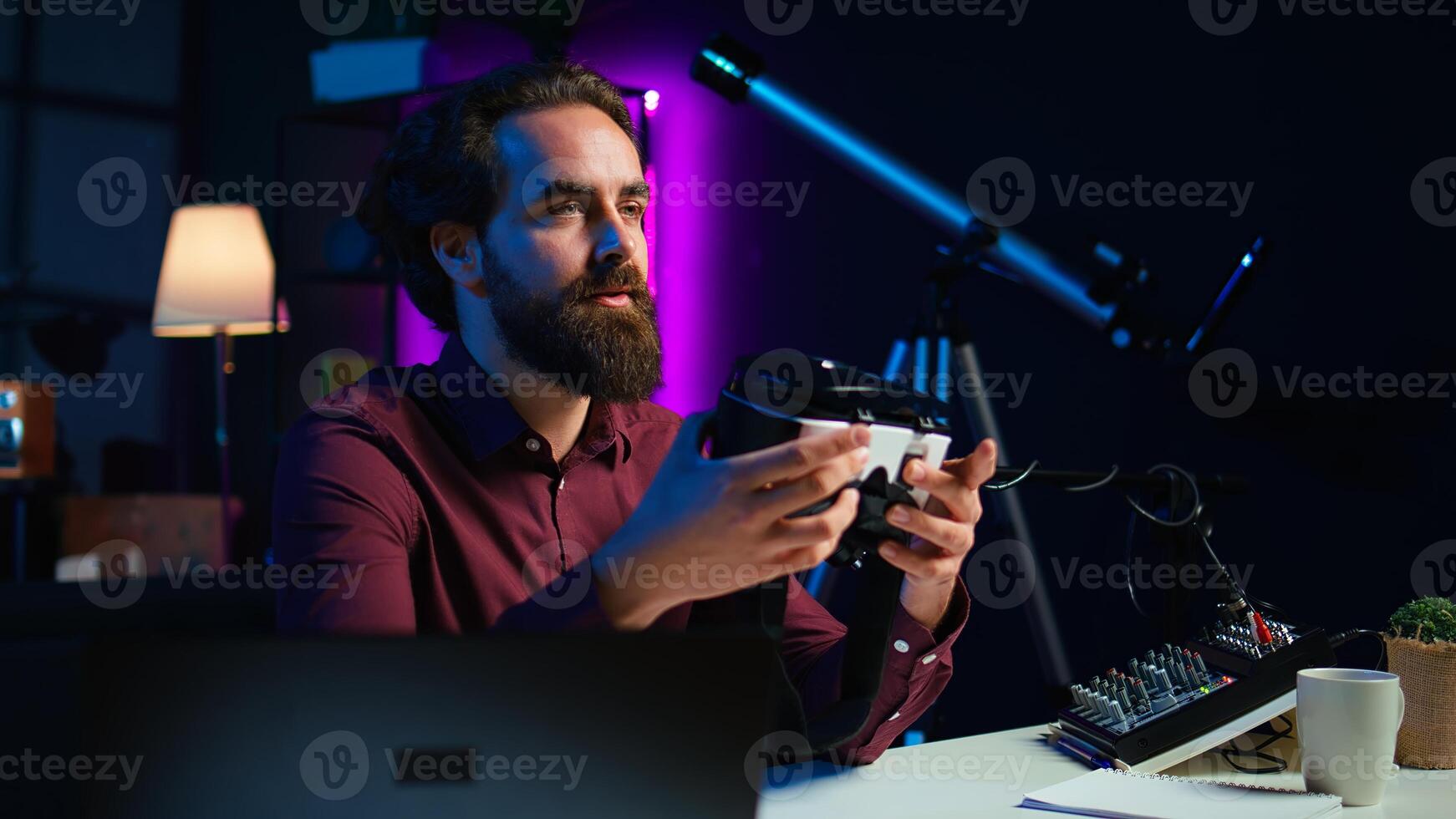 Close up shot of futuristic VR goggles held by man reviewing them for viewers. Internet star filming technology channel vlog for gadget enthusiasts, showcasing virtual reality headset, camera B photo