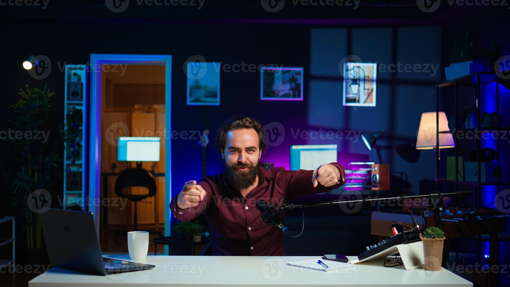 Playful online star using tech equipment to shoot , doing frantic gesturing. Energetic content creator jumping on chair, having fun while filming vlog with professional mic in studio, camera B photo
