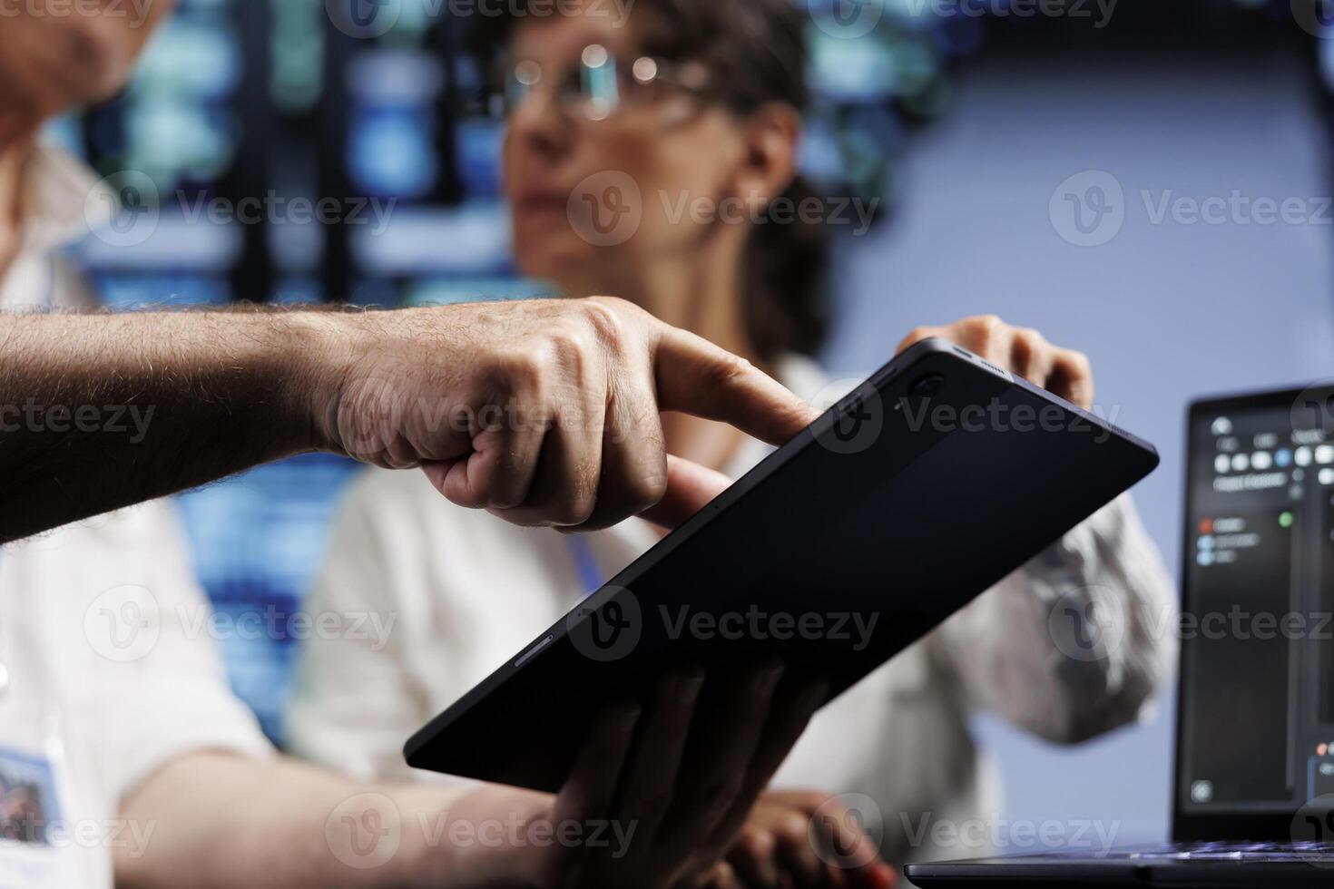 Technical support consultants running analysis on rackmounts used for managing databases, hosting websites and storing files. Efficient professionals auditing high tech facility systems, close up photo