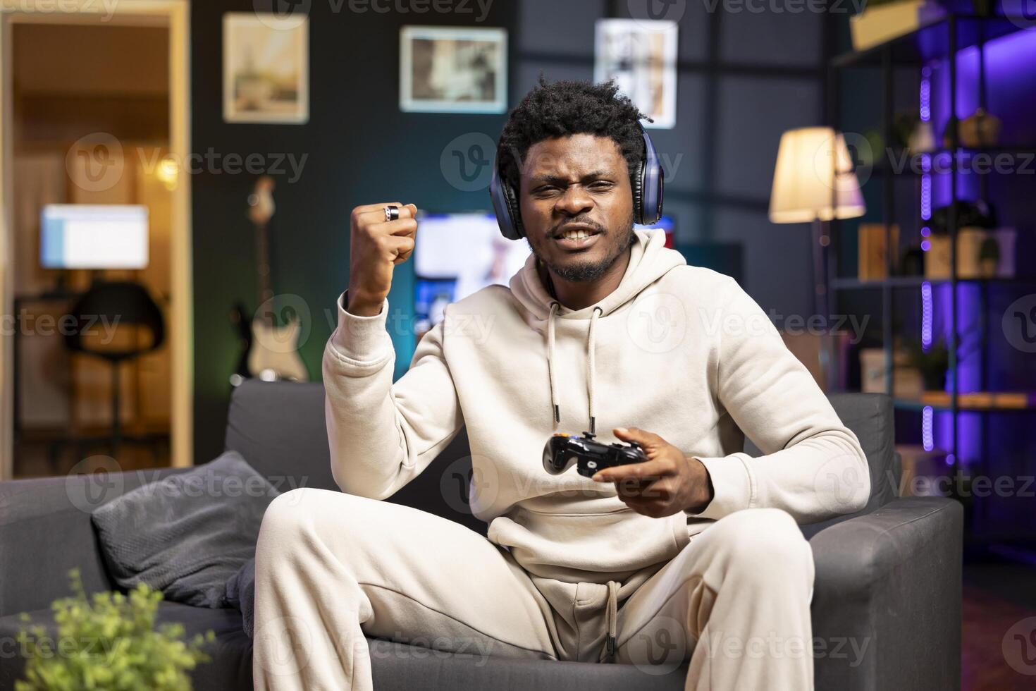 Cheerful gamer feeling excited after finally defeating all enemies and winning, celebrating, punching air. Joyful man congratulating himself after finishing videogame on gaming console photo