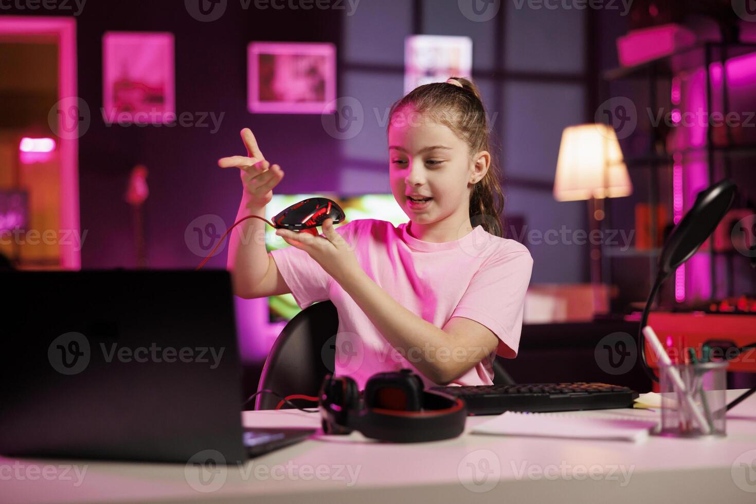 Gen Z media star in studio reviewing gaming mouse in front of camera in personal studio. Cheerful kid filming electronics haul, showcasing wired computer peripheral to audience photo