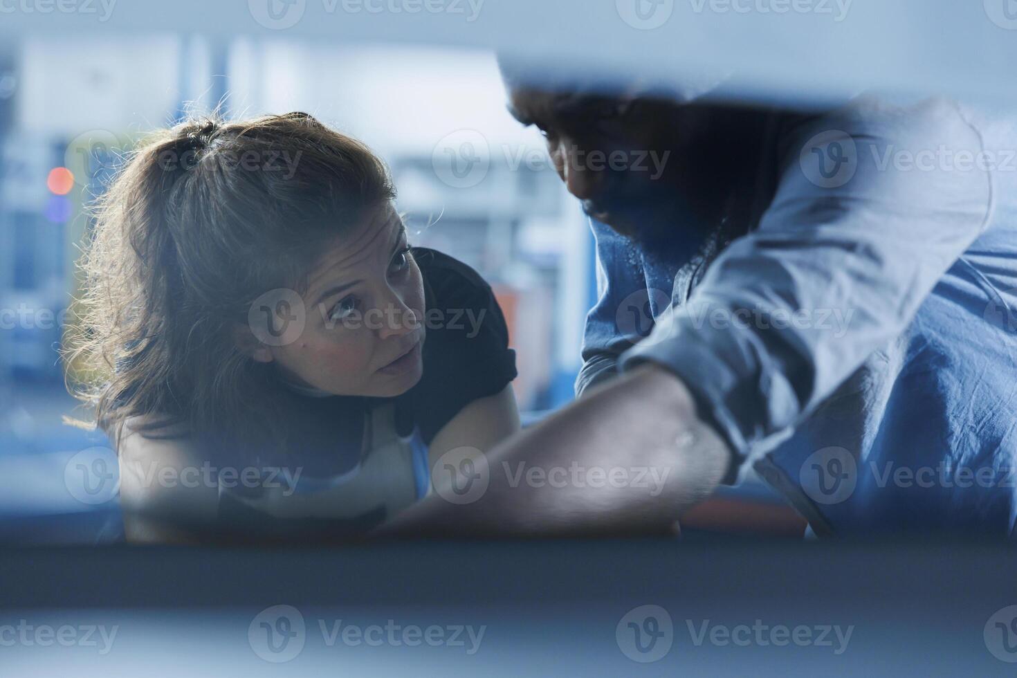 Efficient technician helping client with car checkup in auto repair shop. Employee in garage workplace looking over automobile parts with woman, mending her damaged vehicle fuel tank during inspection photo