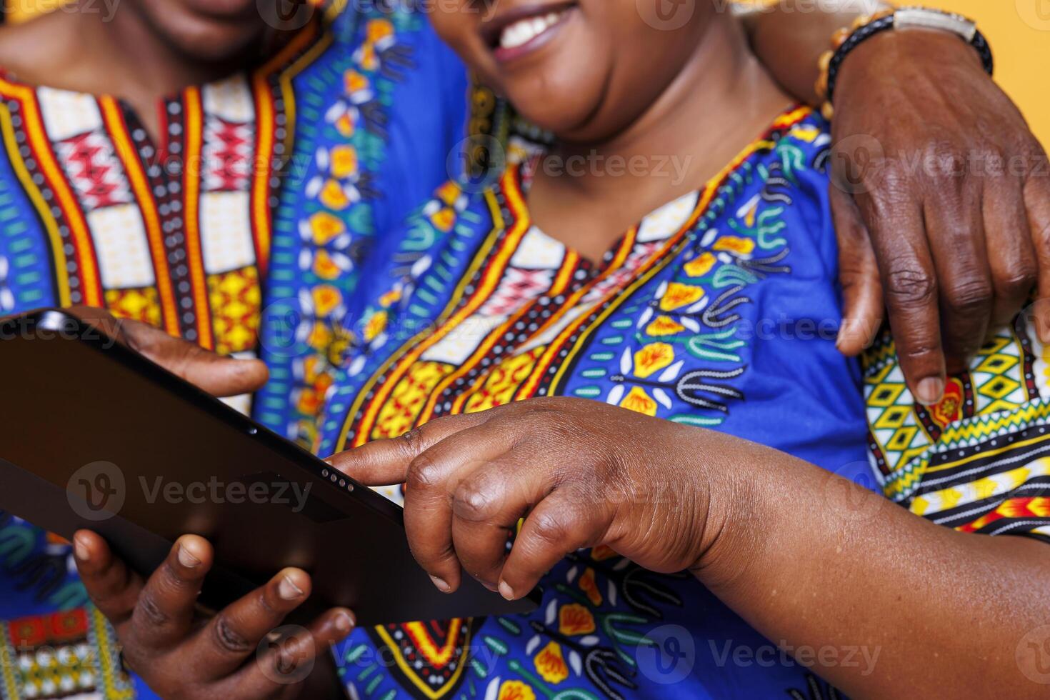 Woman hand tapping on digital tablet touchscreen while hugging with man closeup. African american romantic couple using portable gadget and scrolling internet on screen close view photo
