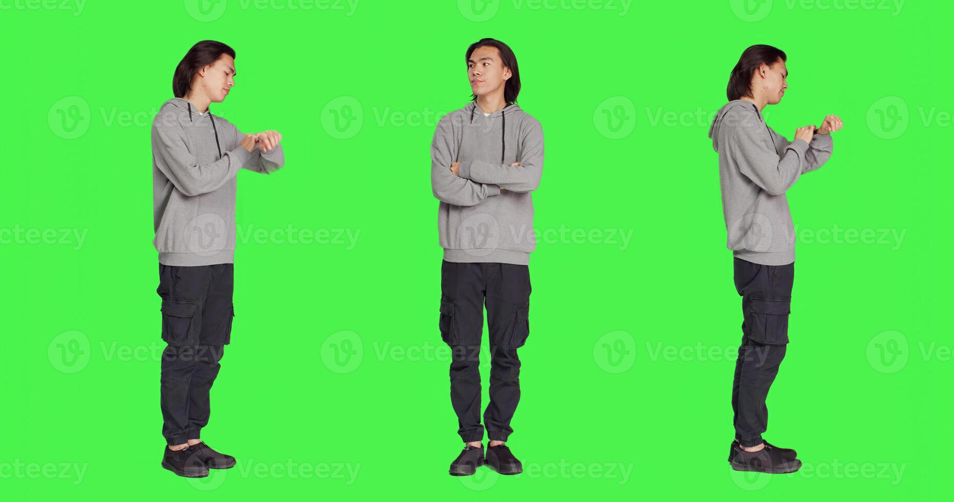 Impatient adult waiting for something in studio, looking around and checking hour on wristwatch over greenscreen backdrop. Asian person being unhappy and irritated, looks at watch. photo