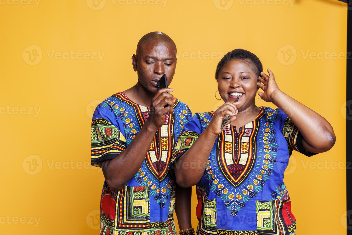 Smiling african american couple singing in smartphone, recording voice together. Cheerful man and woman having fun, enjoying entertainment leisure and using mobile phone as microphone photo