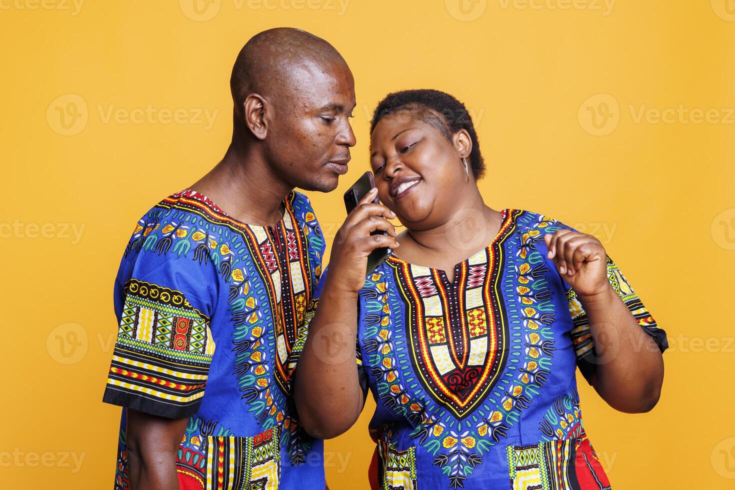Black man and woman couple recording voice with smartphone software app while singing together. Joyful wife and husband singers relaxing, holding mobile phone as microphone photo