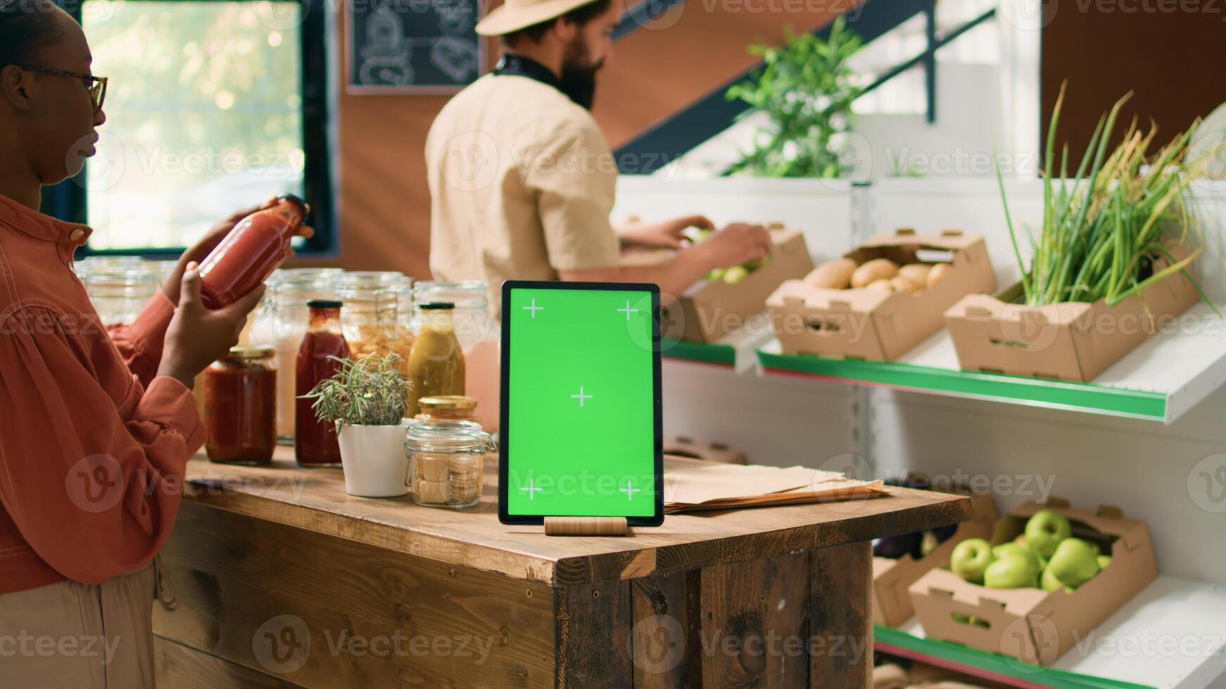 Greenscreen on tablet near client checking bulk products stored in reusable jars, customers supporting nonpolluting lifestyle in local supermarket. Isolated chromakey template on mobile device. photo