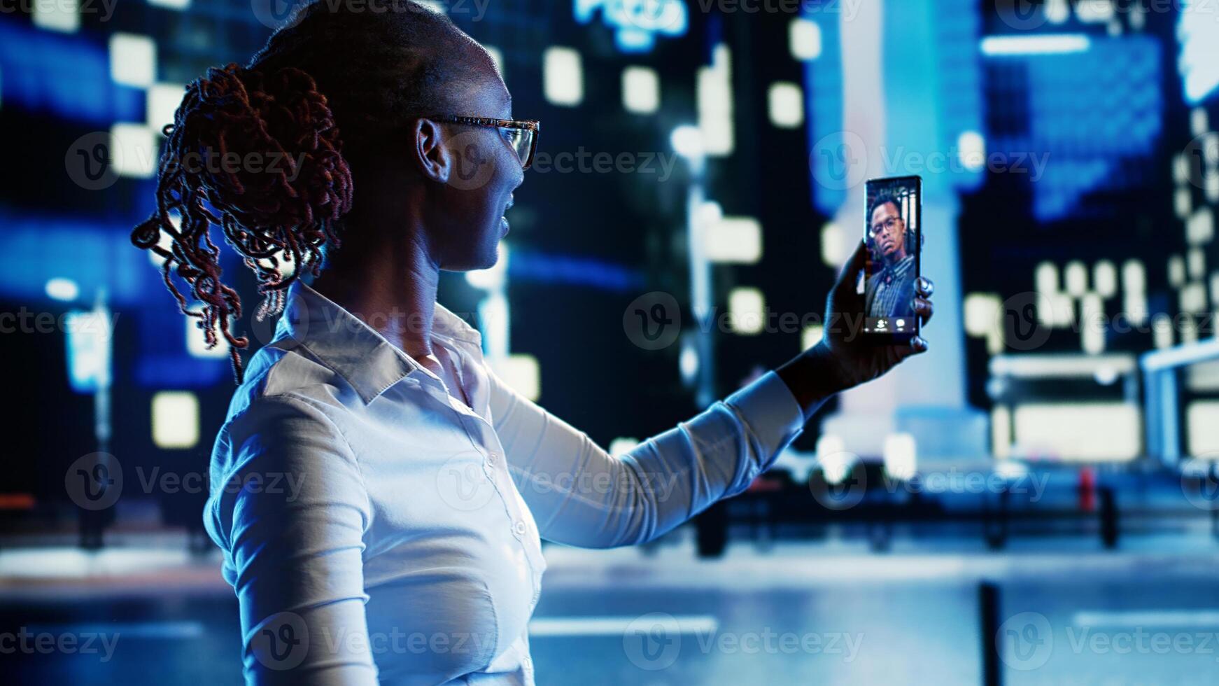 African american woman talking with boyfriend in internet videocall while wandering around dimly illuminated empty city streets at night, needing company to feel safe while walking alone photo
