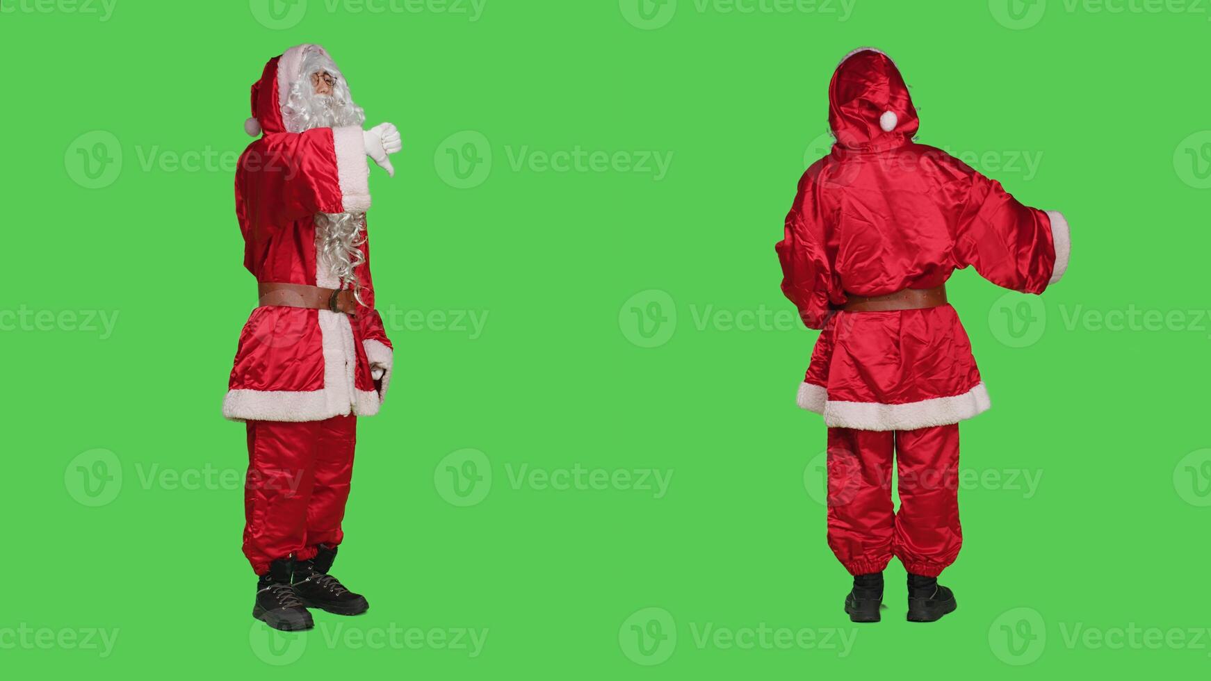 Saint nick shows thumbs down on camera, feeling displeased and expressing disappointment against full body greenscreen. Santa claus character doing dislike gesture in frustration. photo
