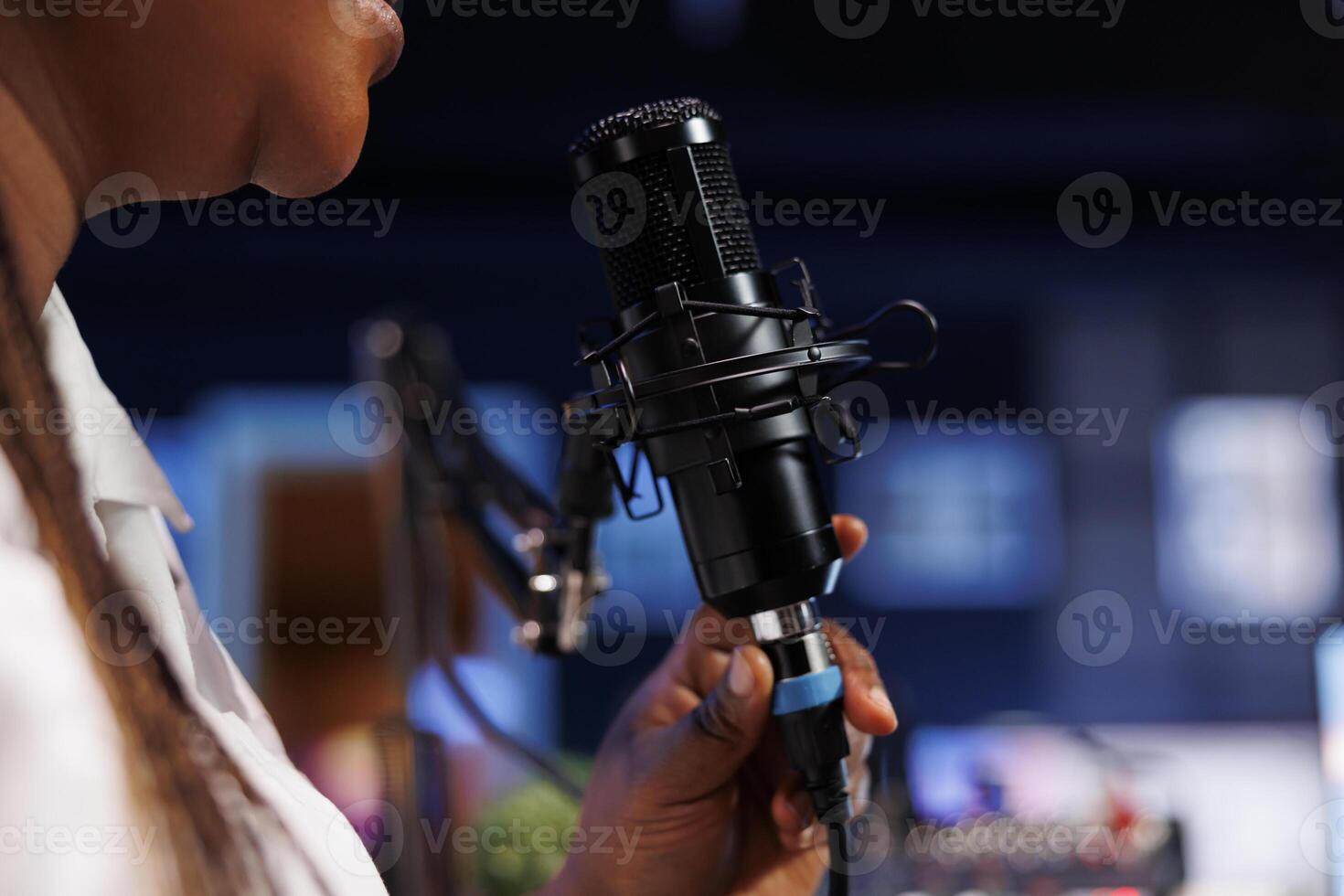 Closeup of a black woman making a vlog for subscribers using a podcast microphone. On air online production, african female host, broadcasting live social media content with audio equipment. photo