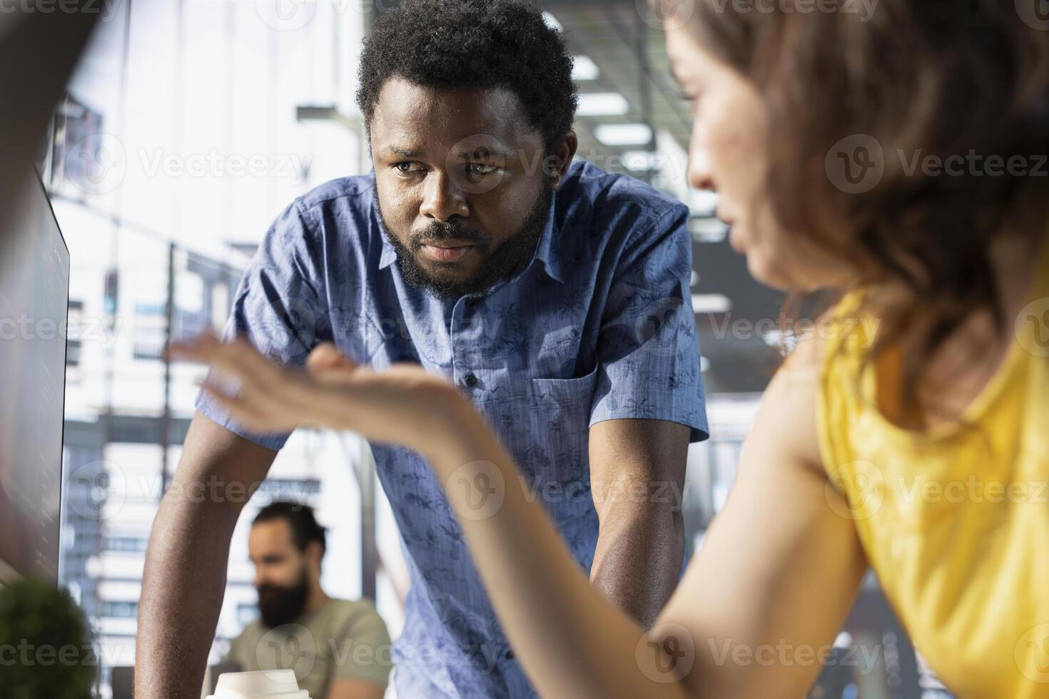 Manager asking accountant to show him business project tasks progress in modern workspace. Team leader overseeing employee working on computer before approaching deadline photo