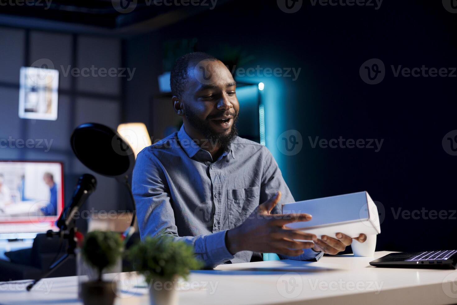 BIPOC tech content creator filming technology review of newly launched smartphone, unpacking it and presenting specifications to audience. Influencer showing mobile phone to subscribers photo