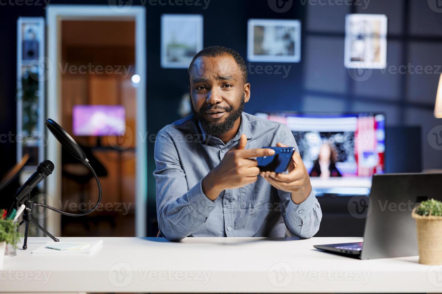 Technology specialist at home holding newly launched smartphone in hand, presenting camera and screen specs. Media star doing cellphone review for viewers, convincing them to buy it photo