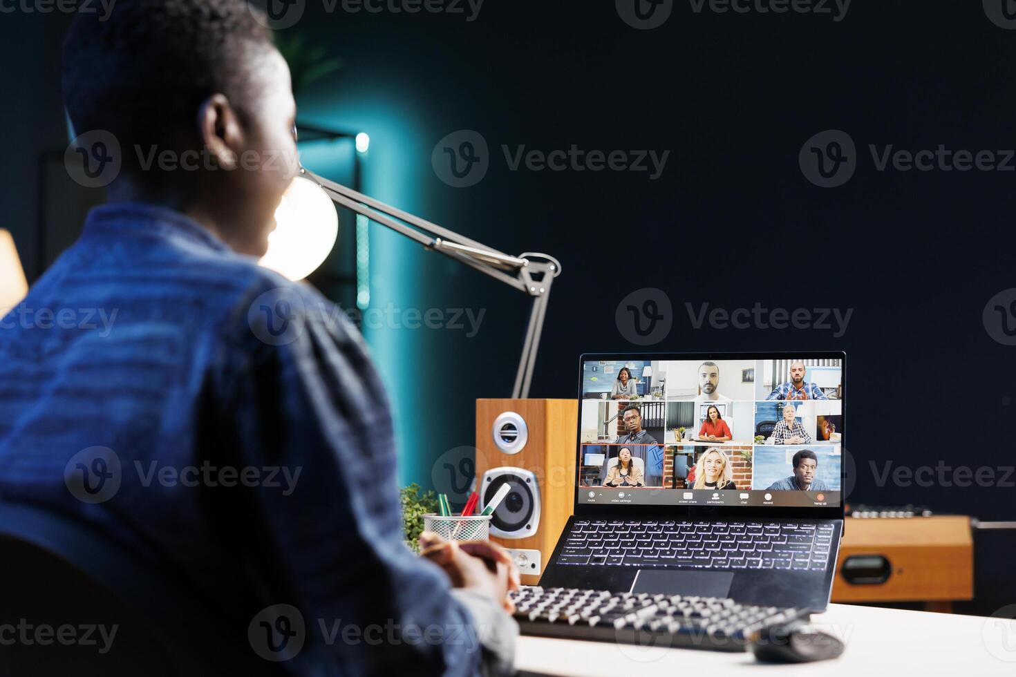 An African American woman and colleagues attending a virtual meeting in her apartment. They are discussing and communicating through a call, fully engaged in the online meeting. photo
