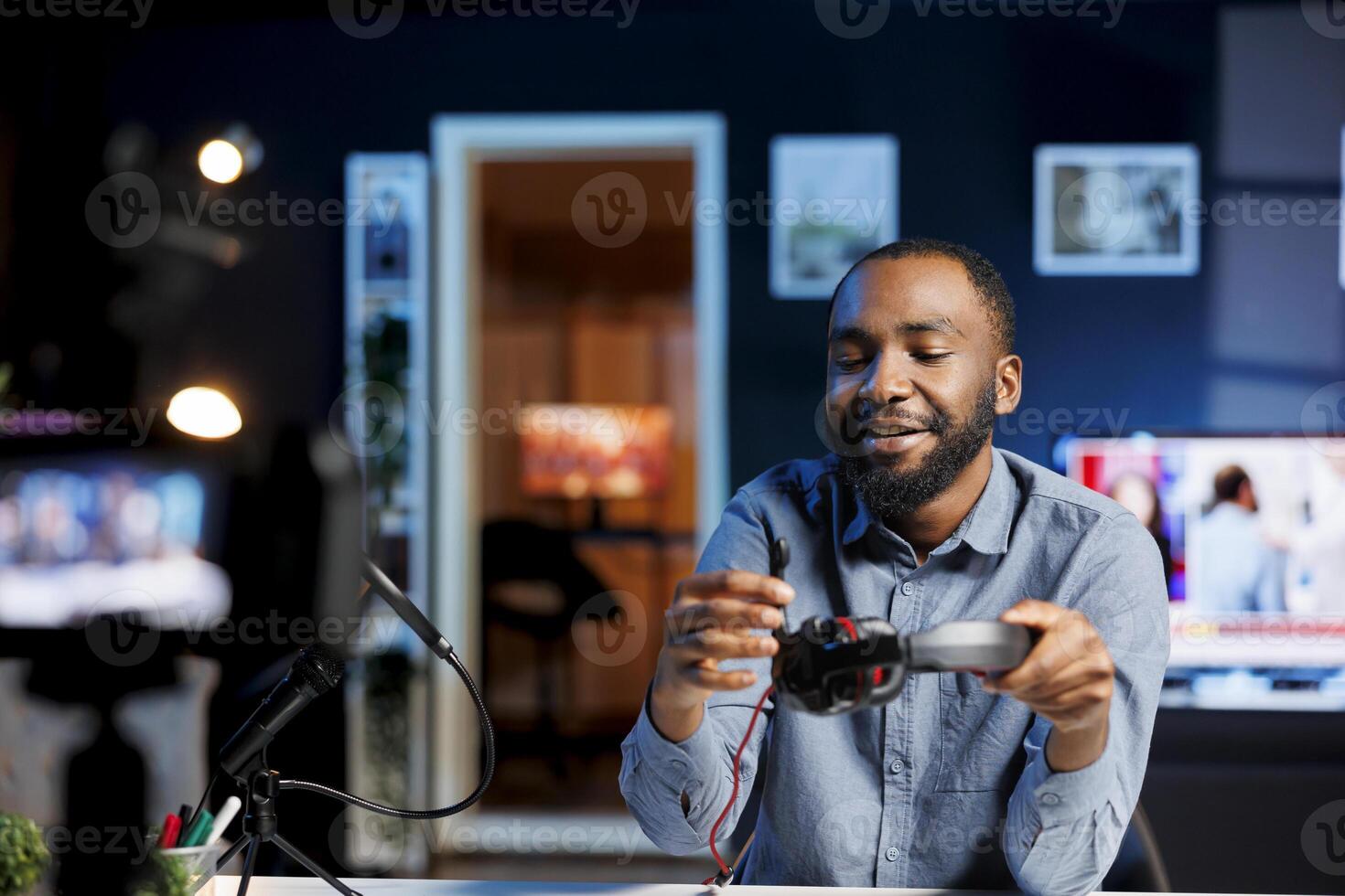 Content creator in dimly lit living room uses camera to film wired headphones review, happy with crisp sound coming from them. Online star satisfied by good maximum volume on music listening device photo