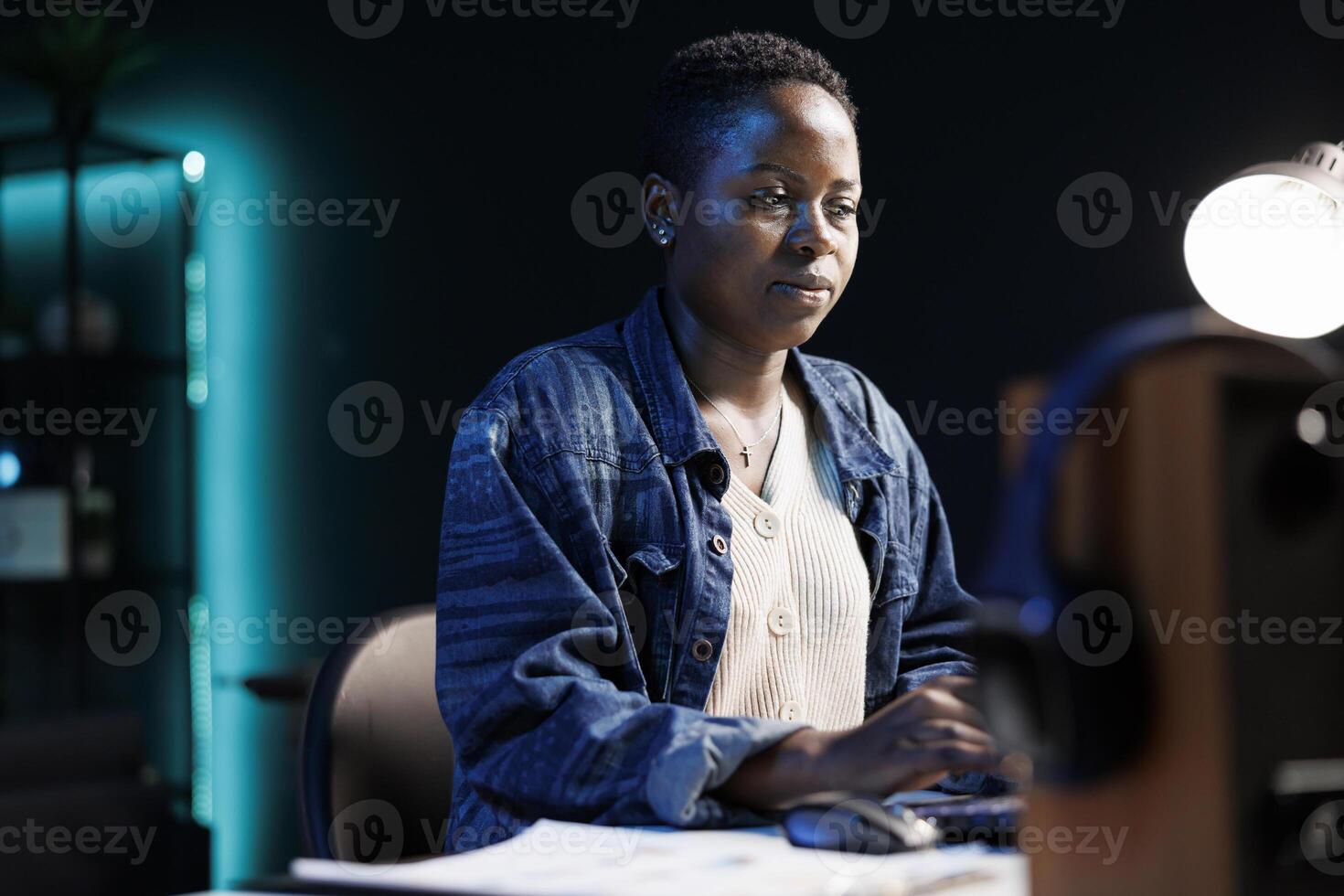 Dedicated African American woman working from a modern apartment. Focused and using her laptop to browse, study, and work on projects. Hardworking and utilizing technology to work from home. photo