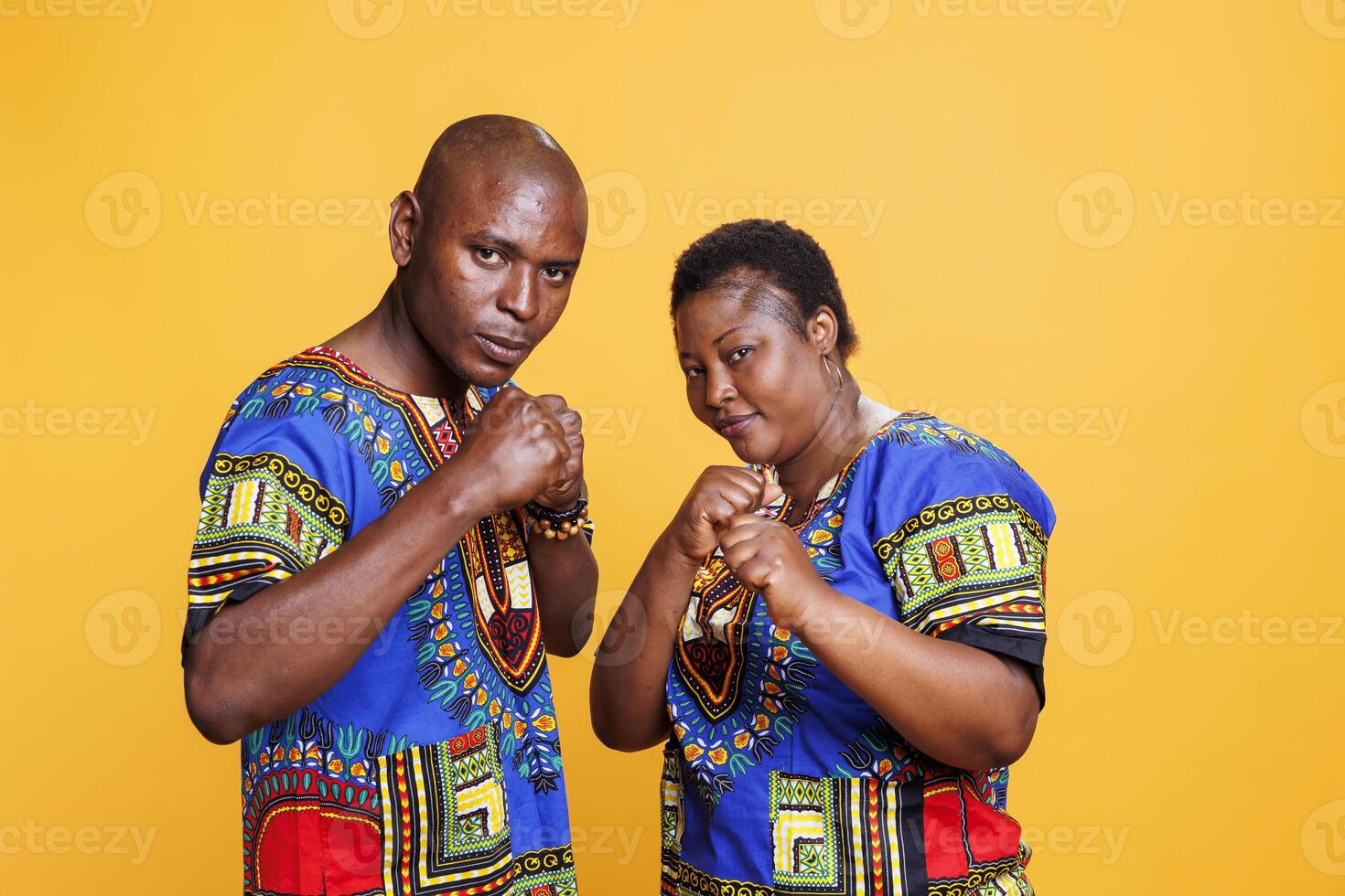Serious african american couple standing in fighting pose with clenched fists and looking at camera. Confident man and woman fighters showing strength and boxing portrait photo