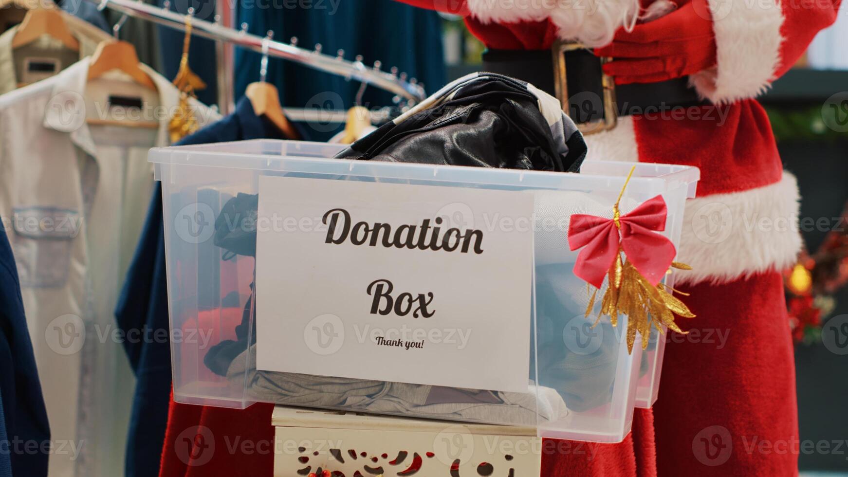 Close up shot of worker dressed as Santa Claus collecting unneeded clothes from customers in donation box, giving them as presentduring Christmas season humanitarian efforts, spreading holiday cheer photo