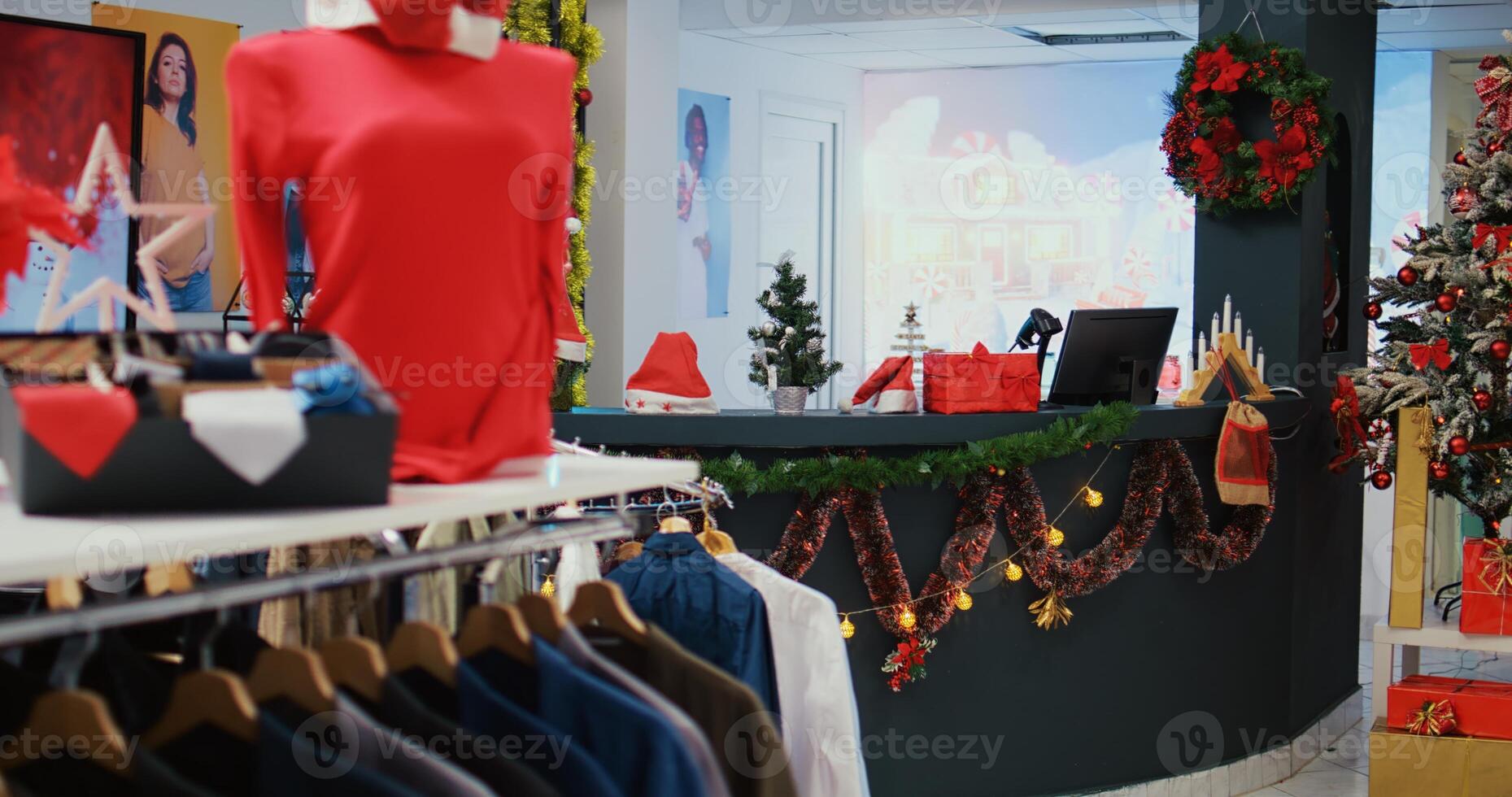 Trucking left shot of festive shopping mall store filled with adorn Christmas tree, garlands and decorations during winter holiday season. Empty xmas ornate fashion shop with clothes on display photo