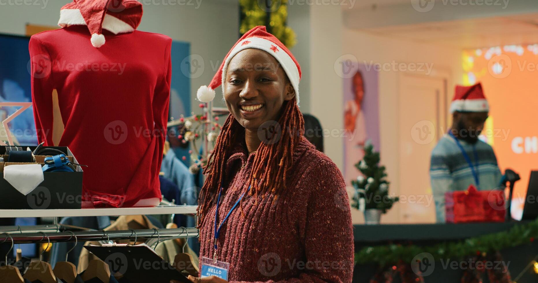 Portrait of cheerful manager browsing through festive clothing display in Christmas shopping store, making sure clothes are ready for customers during winter holiday bargains season photo