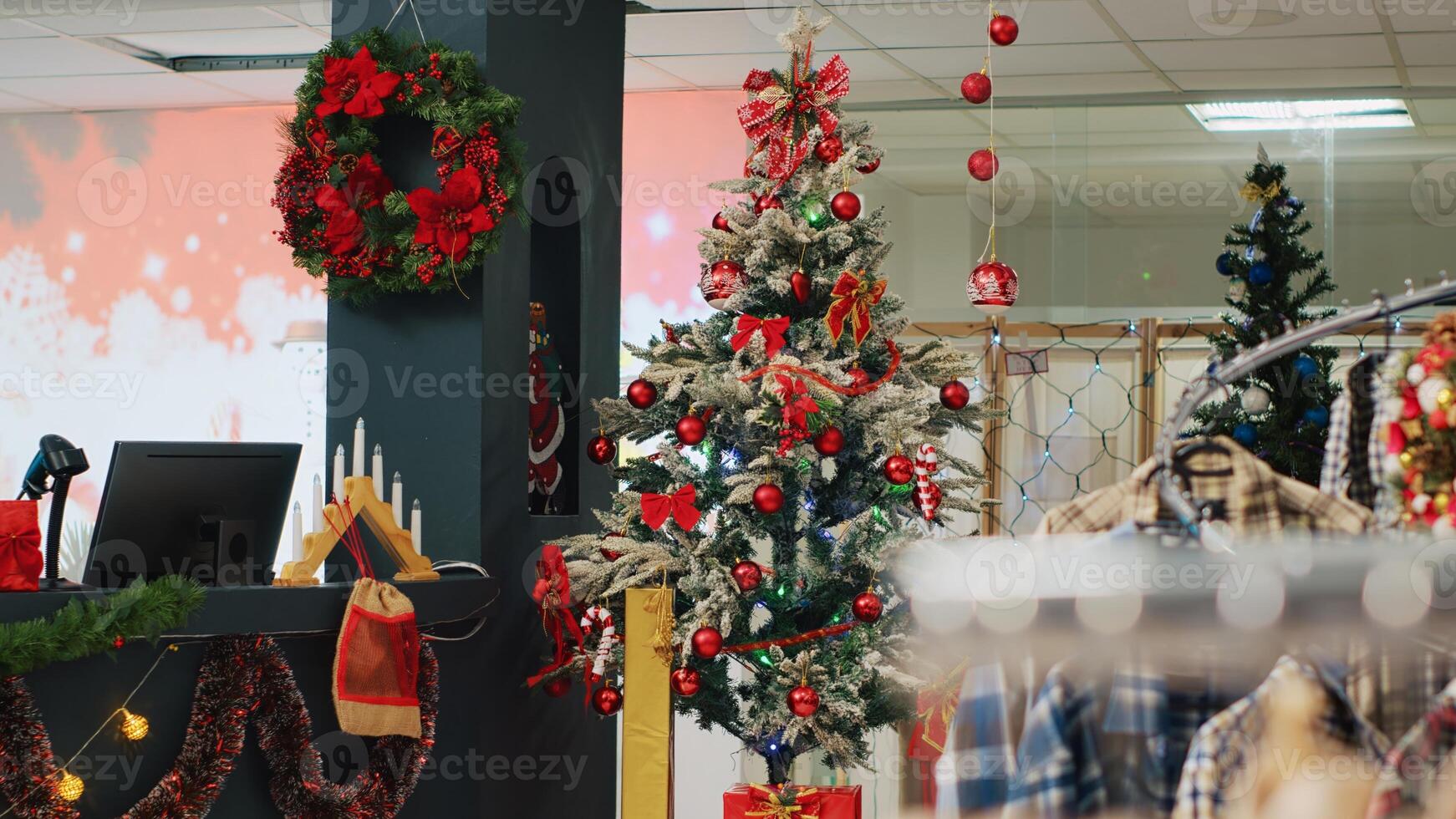Beautifully decorated Christmas tree in clothing store waiting for customers looking for gifts during winter holiday season. Xmas adorn fashion boutique in mall with clothes on sale photo