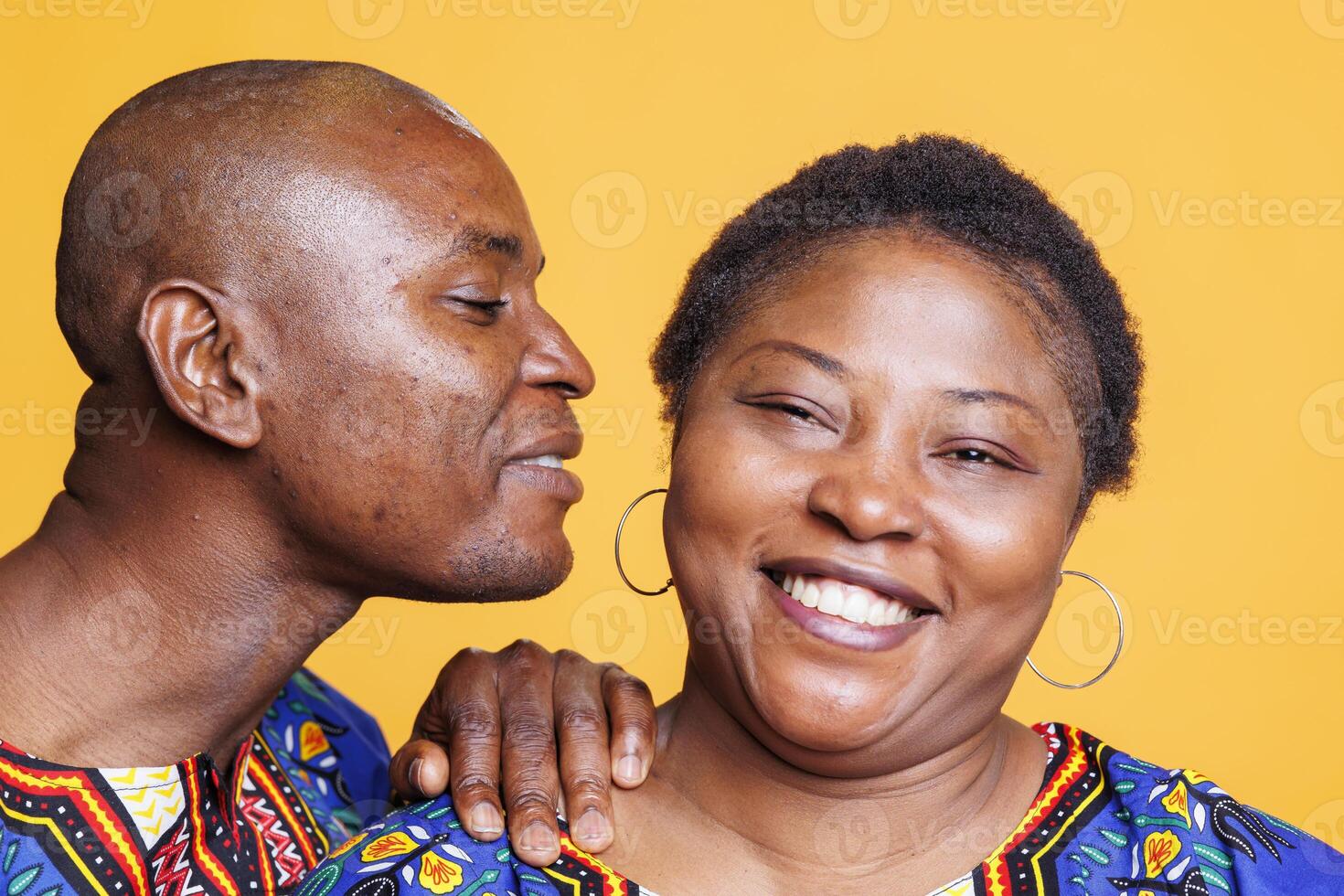 African american man whispering romance and love words to wife studio portrait. Cheerful happy woman smiling and looking at camera while hearing husband telling secret in ear photo