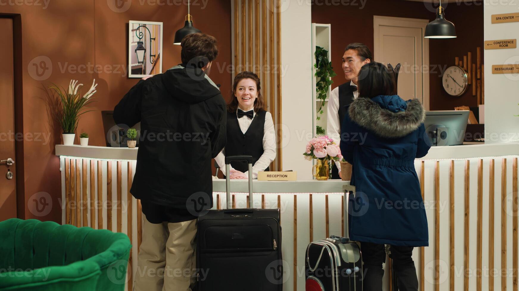Active tourists enter mountain resort, talking to hotel staff about room check in carrying skis and snowboard. Winter sports lovers preparing for leisure activity on alpine slopes. Handheld shot. photo