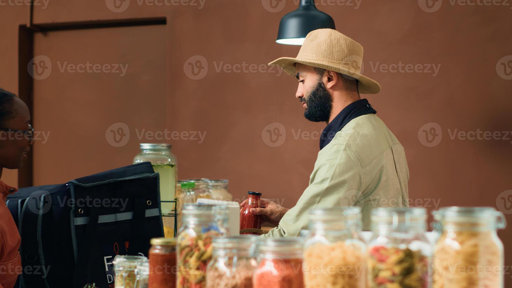 Vendor preparing groceries order for home delivery, putting bio organic produce in thermal backpack. African american employee coming to pick up fruits and veggies for local eco store clients. photo