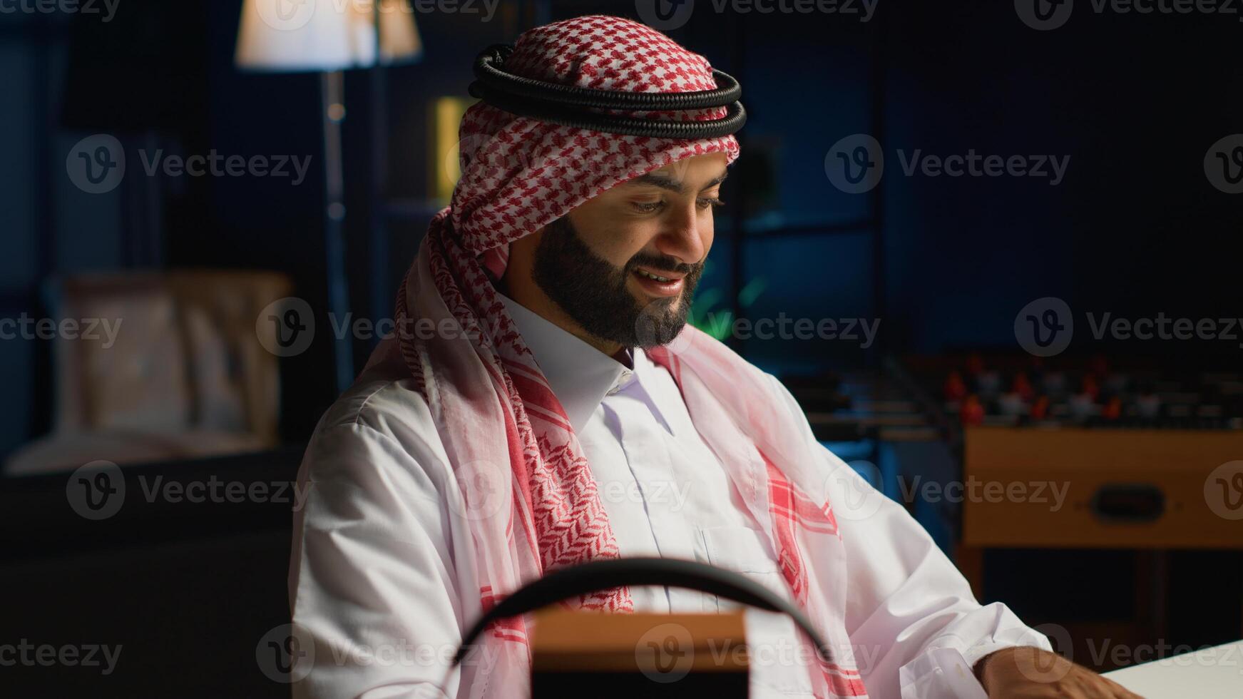 Smilling arab man doing online shopping, using computer to look up tech products to buy. Middle Eastern person adding credit card payment method on secure website, ordering with instant delivery photo