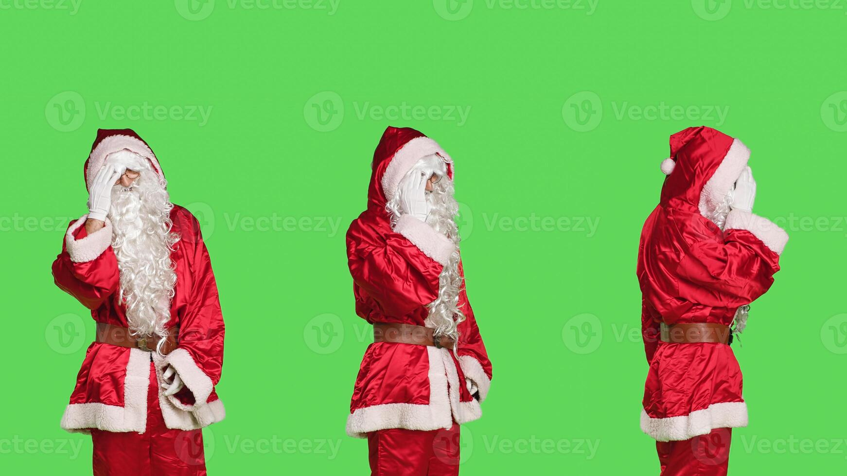 Father christmas with painful headache standing in studio over greenscreen backdrop, unwell man in saint nick red suit. Sick festive character with migraine feeling hurt, pain on holiday. photo