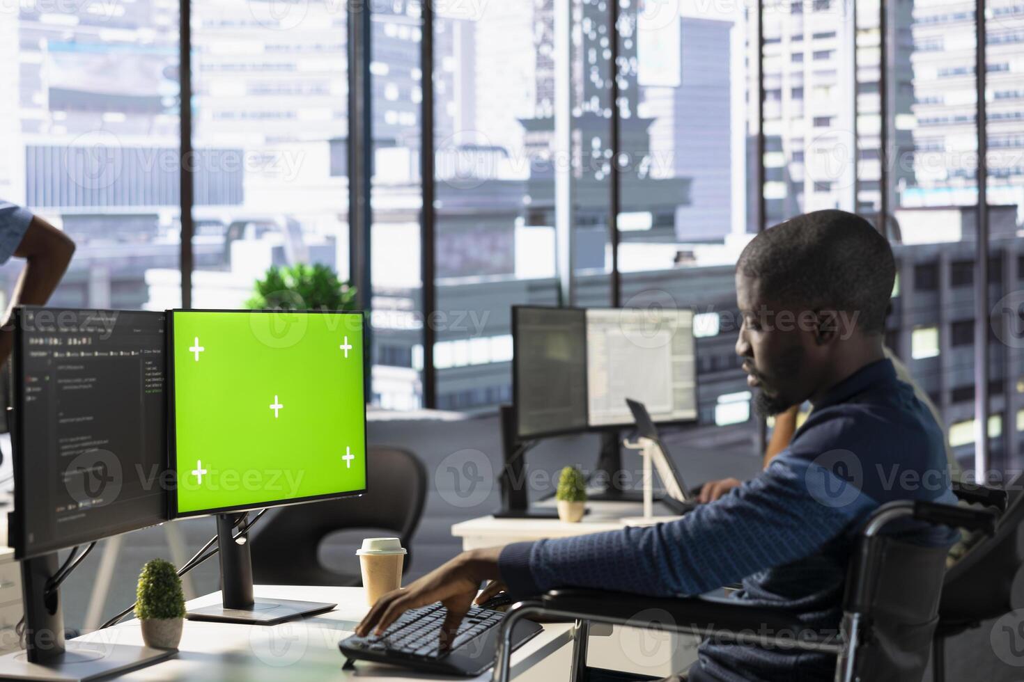 Person with paraplegia testing and deploying programs and systems on green screen PC. Software engineer in wheelchair checking code on mockup PC, sitting at desk in office photo