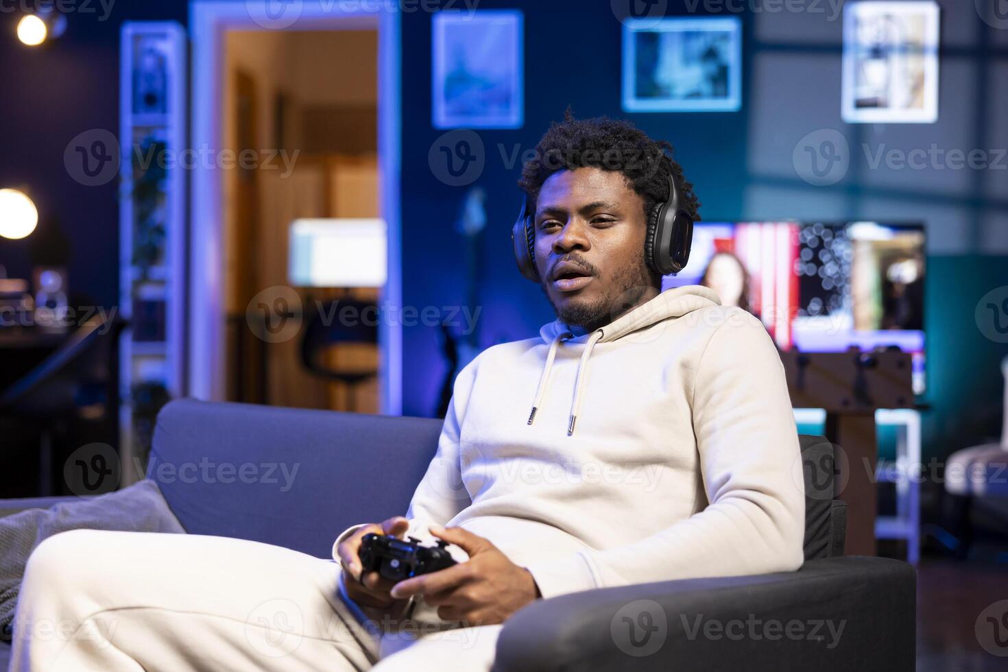 Gamer at home sitting down on couch, enjoying games on laptop during leisure time. Man sitting on couch in living room, playing videogame on notebook, relaxing after work photo