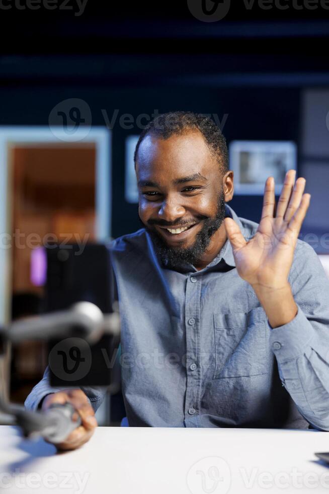 African american content creator using smartphone to film vlog channel intro for online streaming platforms. Media star greets fanbase, presenting today topic, recording with phone photo