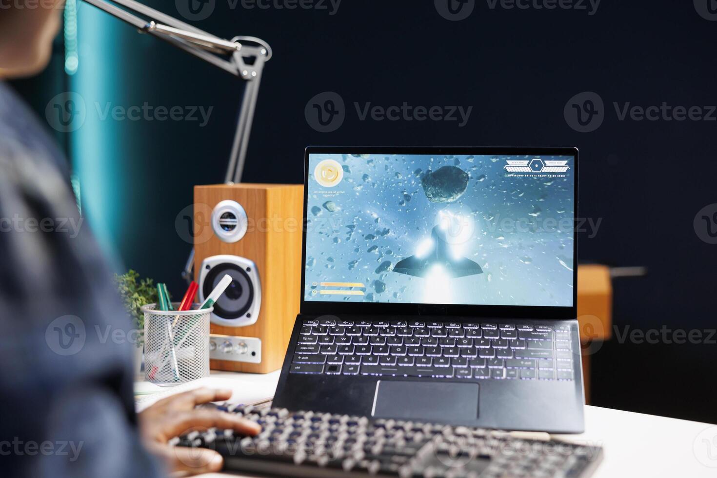 A young African American woman competes in an online game, fully engaged with her laptop and wireless headset, enjoying the excitement of gaming from her apartment. photo