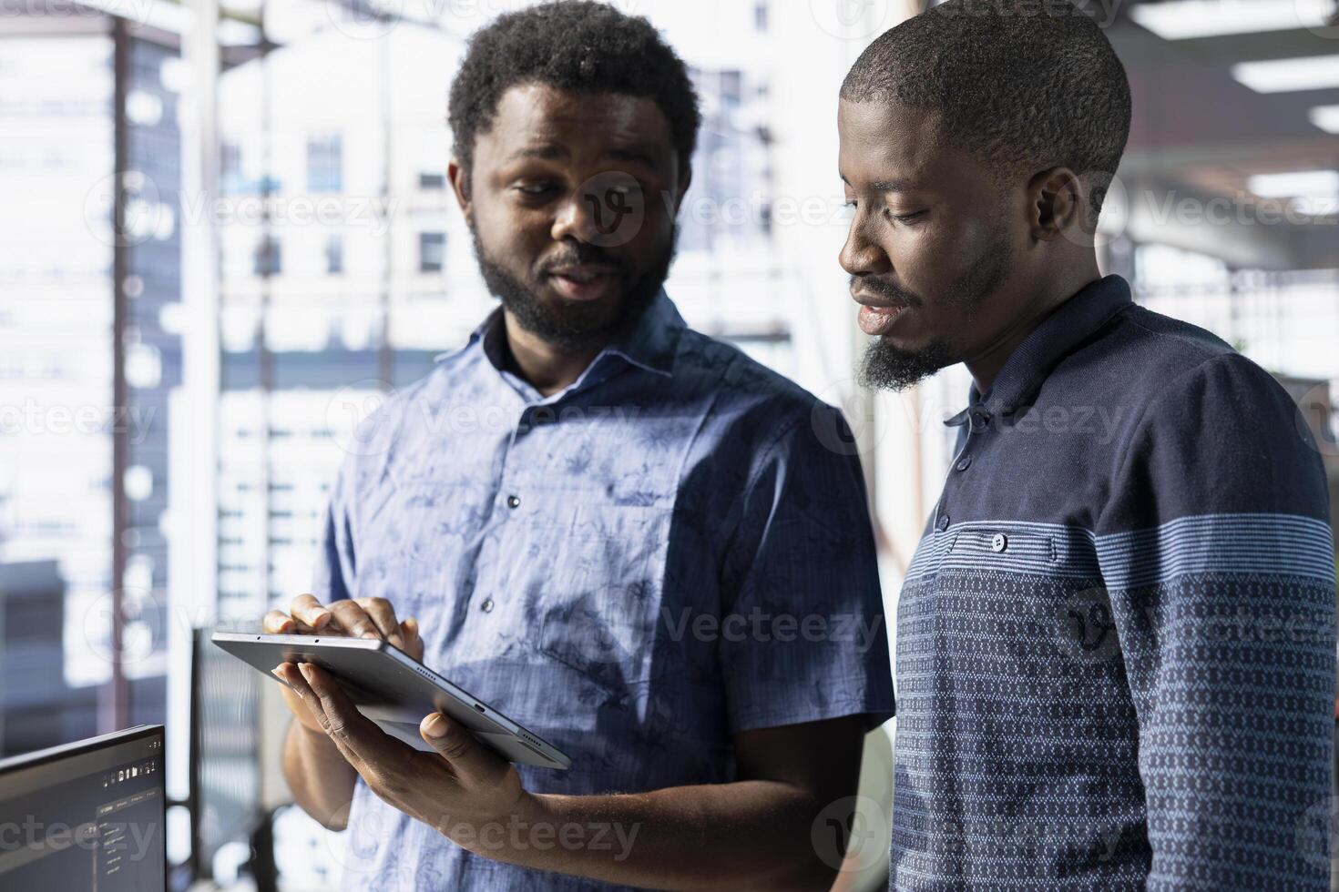 Coworkers looking at tablet, managing cloud computing resources and platforms to train machine learning models. Teamworking colleagues brainstorming while monitoring company systems photo