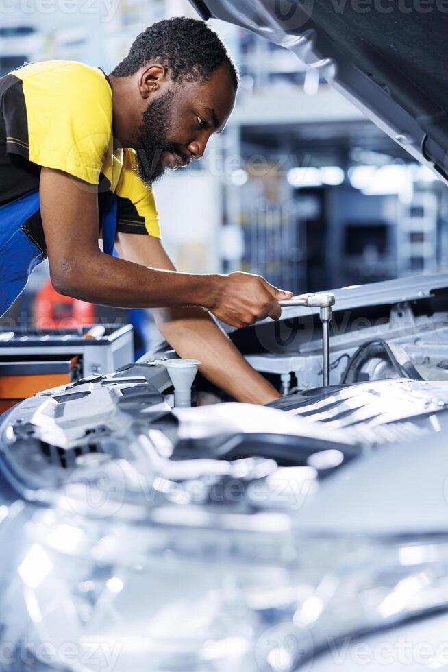 Mechanic in car service using professional mechanical tool to repair broken lights system. Diligent worker in garage fixing client automobile, ensuring optimal automotive performance photo