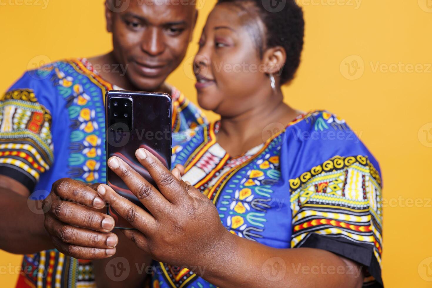 African american couple holding smartphone in hand and using application together. Man and woman spouse scrolling social media and reading message on mobile phone closeup photo