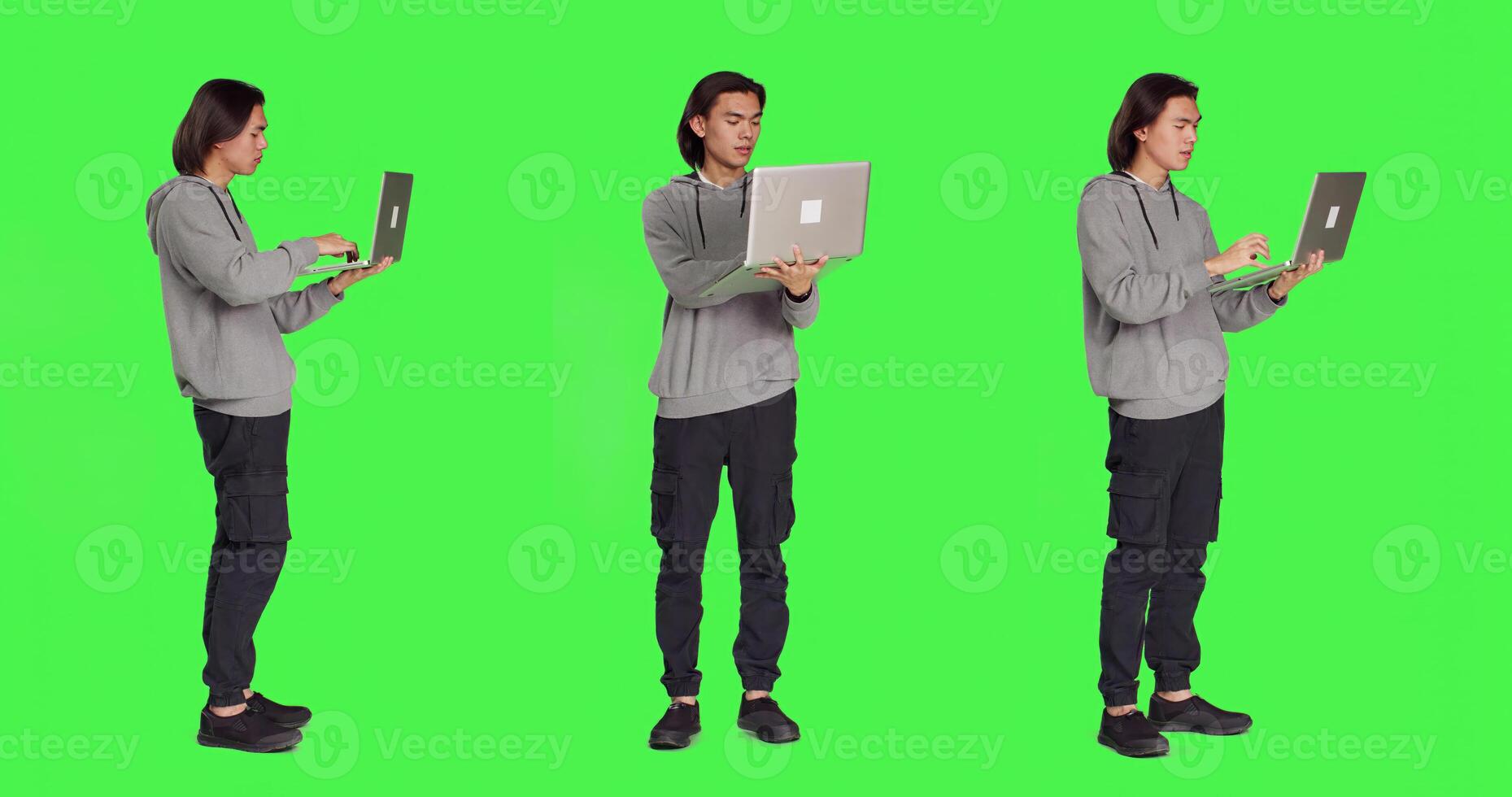Modern man navigating webpage on laptop standing over full body greenscreen backdrop, browsing online website using wireless pc. Young guy checking social media page working on business. photo