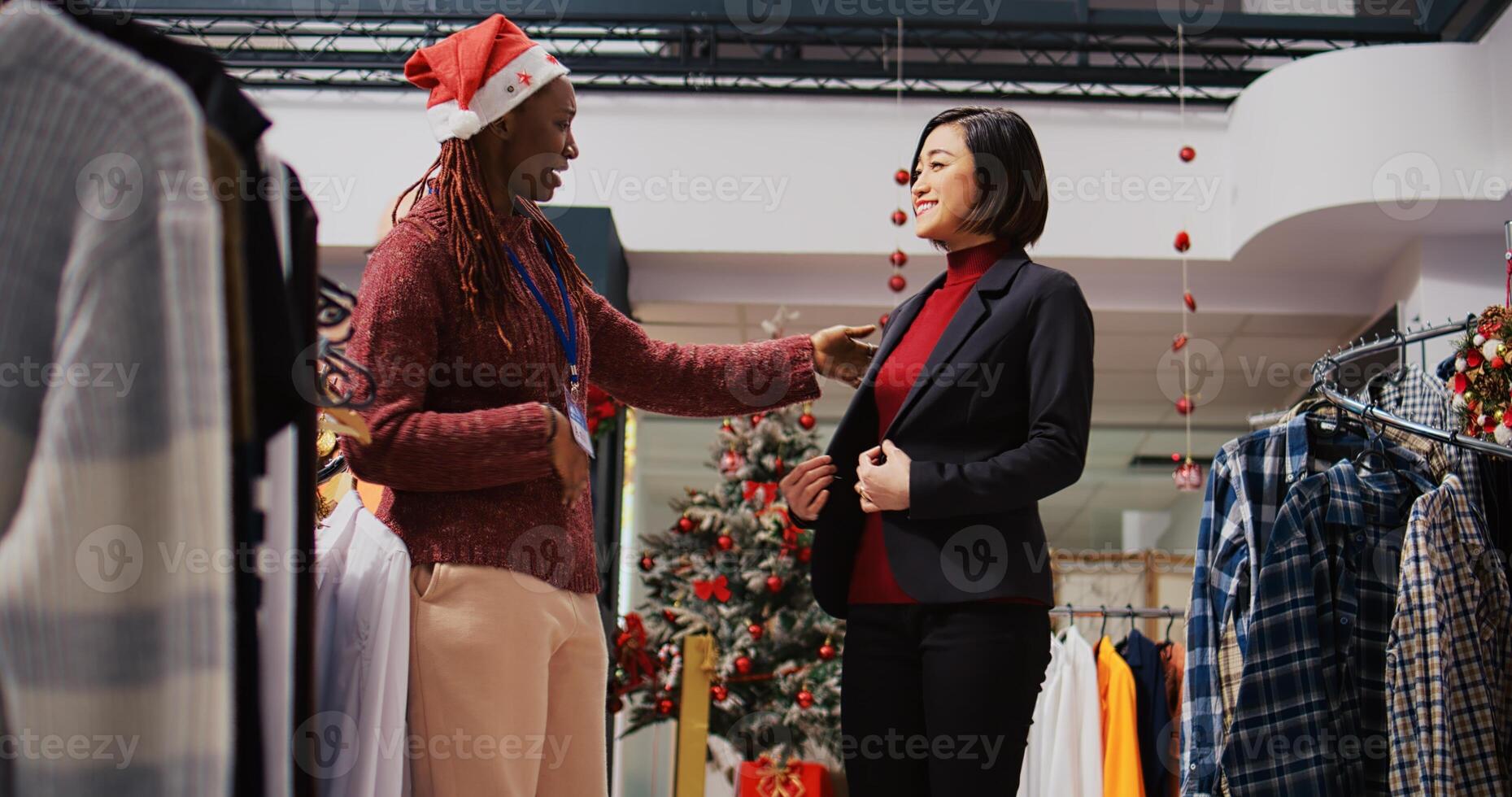 Ground level shot of customer spinning around in festive decorated clothing store, excited to show african american employee elegant blazer fitting perfectly after trying it on photo